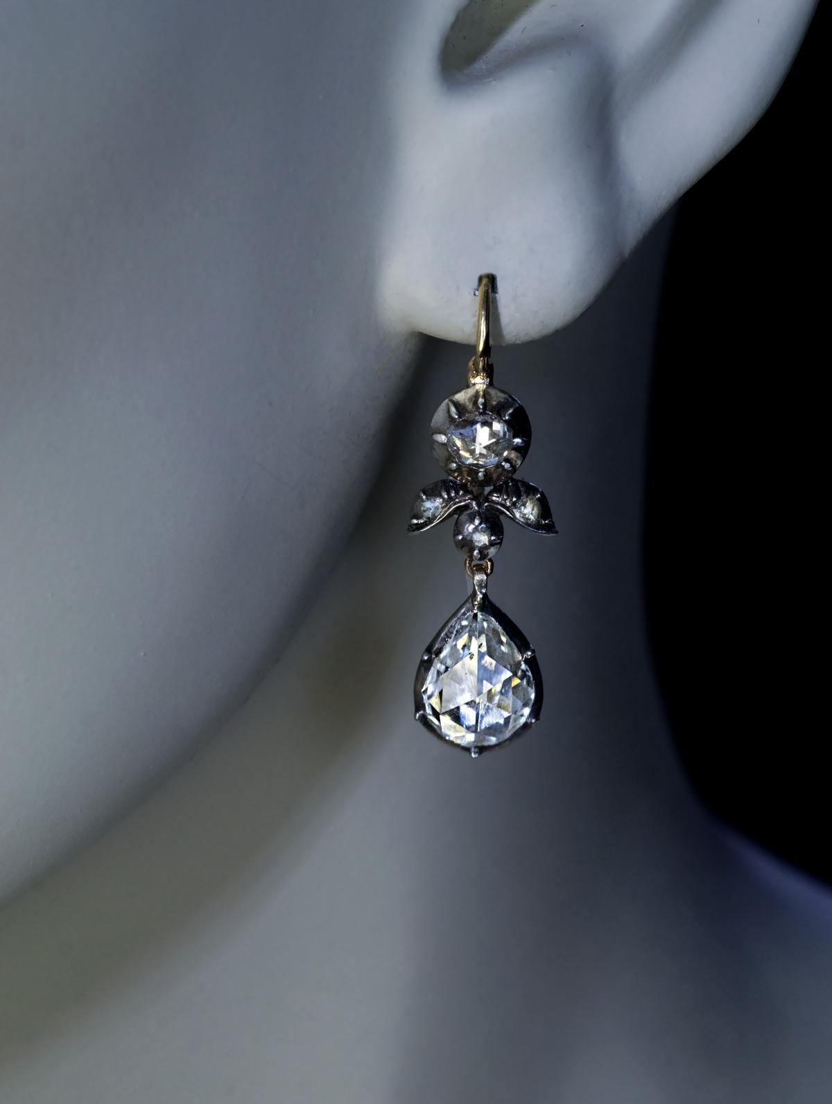 Circa 1800 – 1830

This pair of rare Georgian era dangle earrings is set with sparkling antique rose cut diamonds. The diamonds are set in silver and backed in 14K gold.

The two drop-shaped diamonds measure approximately 9.3 x 7.2 x 2.7 mm and 9.3