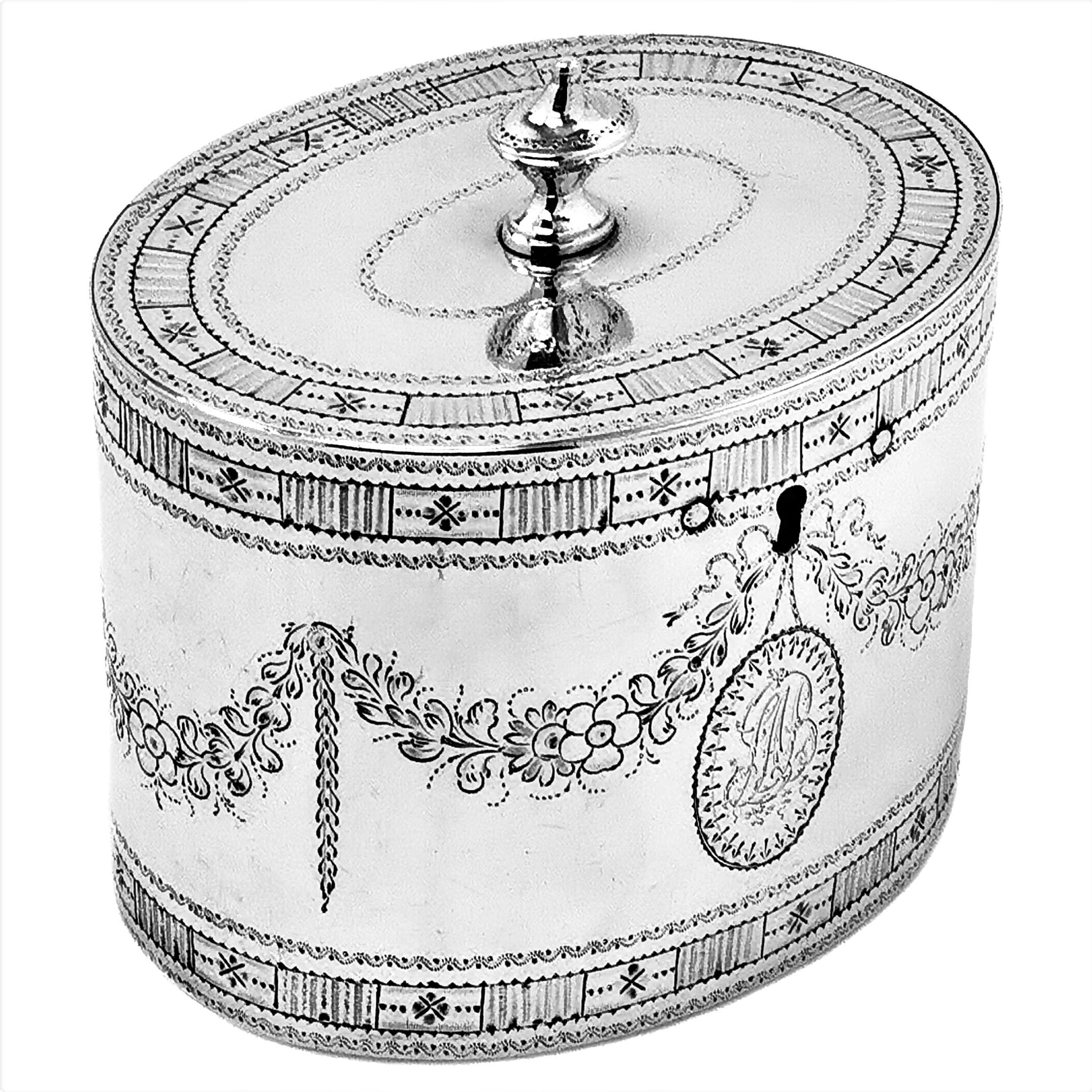 A beautiful Antique George III is a classic oval can shape Tea Caddy and is decorated with an ornate engraved border on both top & bottom rims of the body and around the rims of the lid. The body of the Caddy also includes a floral swag and bow