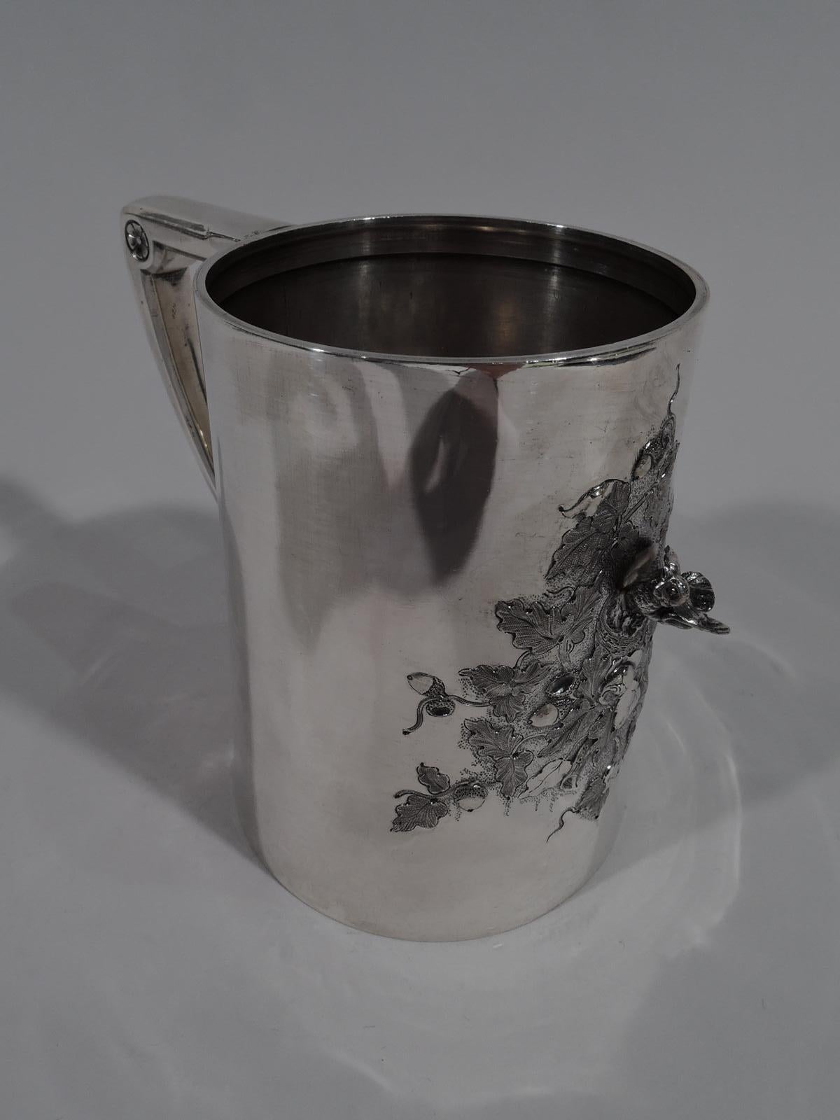 Bird’s nest sterling silver baby cup. Made by Gorham in Providence in 1868. Straight and upward tapering sides, and bracket handle. On front is cast figure of nesting bird mounted to chased and engraved irregular ground with leaves and acorns. A