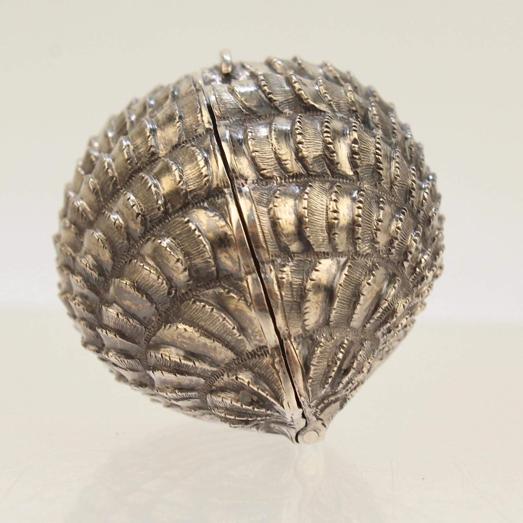 A very rare English sterling silver nutmeg grater.

It is modeled as a full bodied scallop seashell and has a cover that reveals a hinged steel grill or grater.

The interior rim bears hallmarks for Hilliard & Thomason.

A very fine addition to any