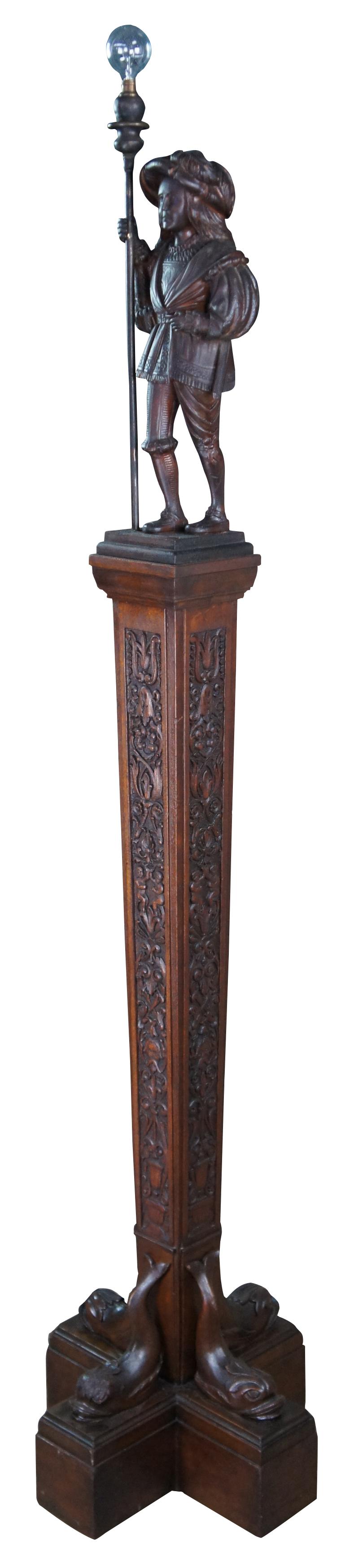 A rare and one of a kind antique figural carved oak floor lamp, circa 1920s. Meticulously carved with amazing detail throughout. Features a swiss guard with torchiere staff atop a square tapered heraldic column leading to dolphin base. Columnar