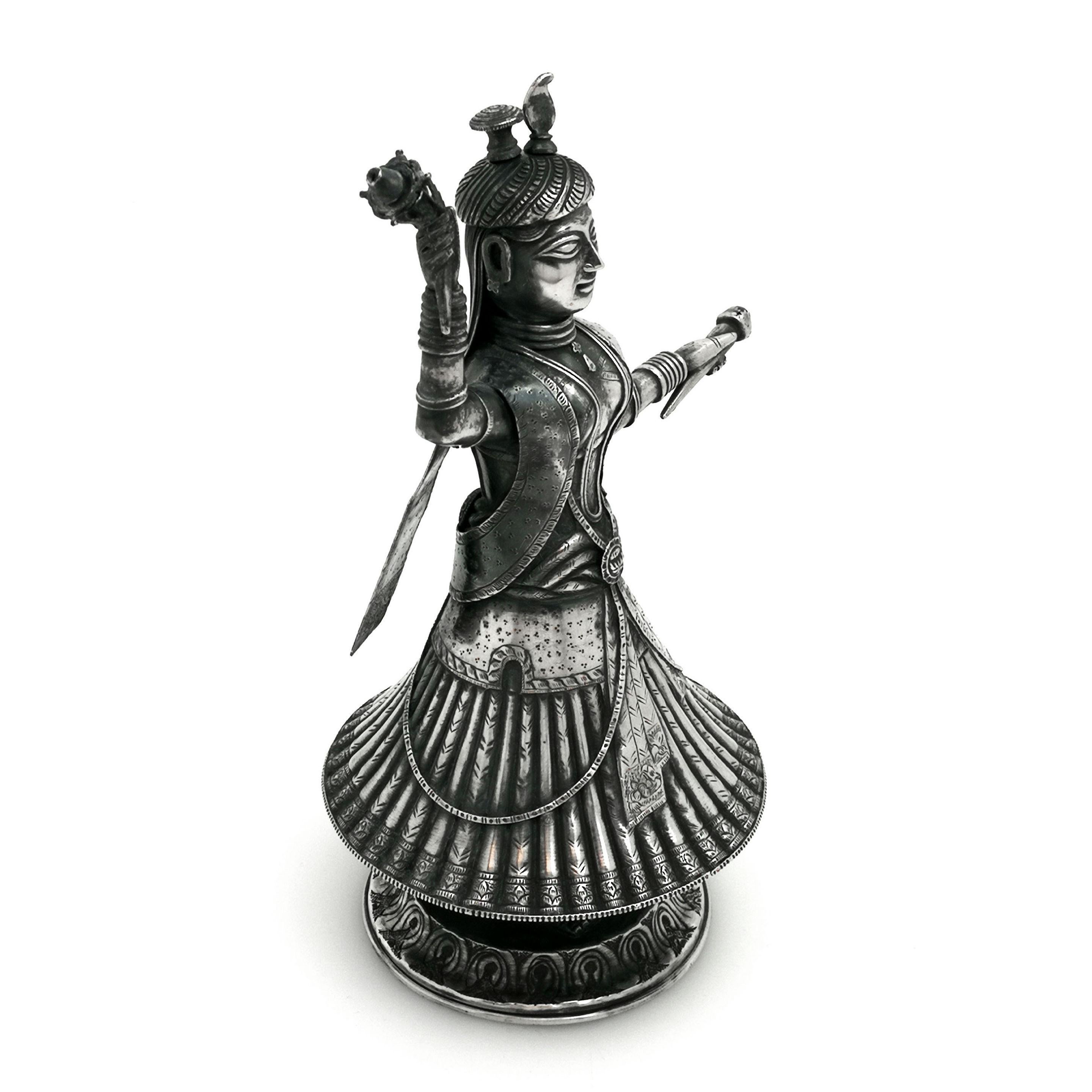 A magnificent antique Indian solid silver rose water sprinkling decanter bottle. The decanter is formed in the shape of a dancer with a whirling skirt. The interior of the bottle is ingeniously divided into two sections with the stoppers designed as