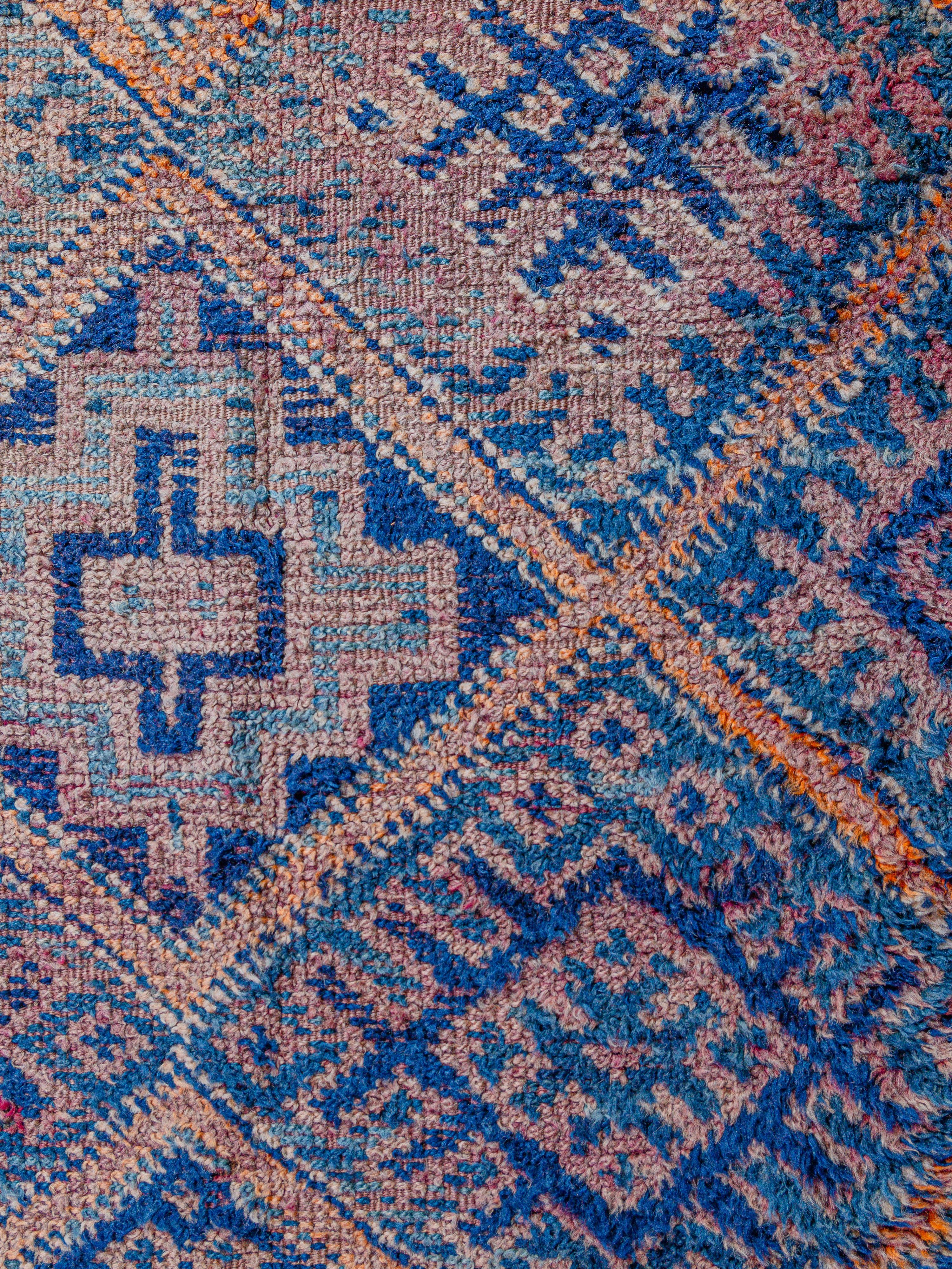 Ein klassisches, antikes Beni M'Guild mit einem Feld aus kunstvoll gefüllten Rauten, geknüpft in natürlichem Indigo und Schattierungen von Magenta, Apricot und Orange. Artistische Interpretationen von Hamas, Kreuzen, Dreiecken und anderen