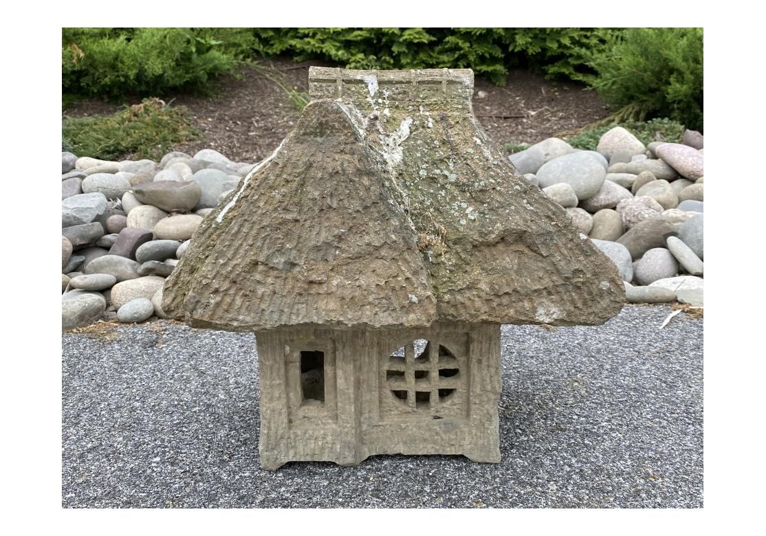 Rare and complete antique Japanese carved stone architectural model of a traditional Folk Cottage. The front of the cottage has an entrance door and a round window with grid patterning, the sides have a circular window and a moon shaped window. The