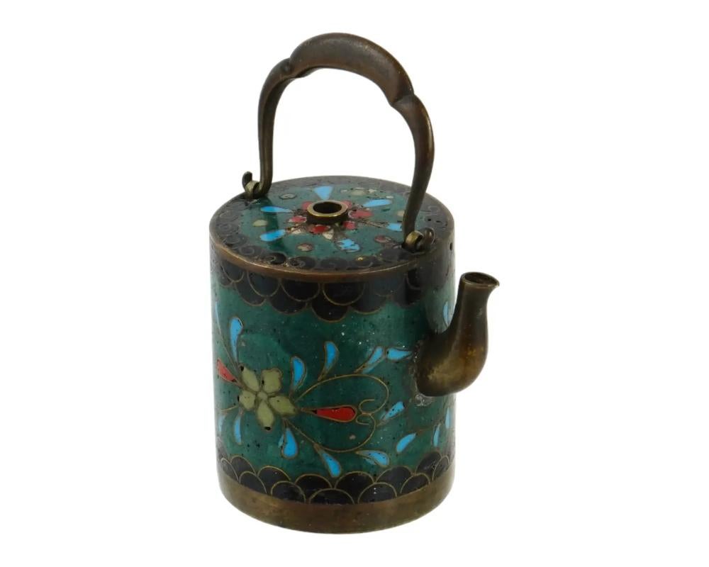 An antique Japanese copper water dropper with cloisonne enamel design. Meiji period, 1868 to 1913. Cylinder shape, moveable top handle. Polychrome floral pattern against the dark green background. A water-dropper, or suiteki, is used in East Asian