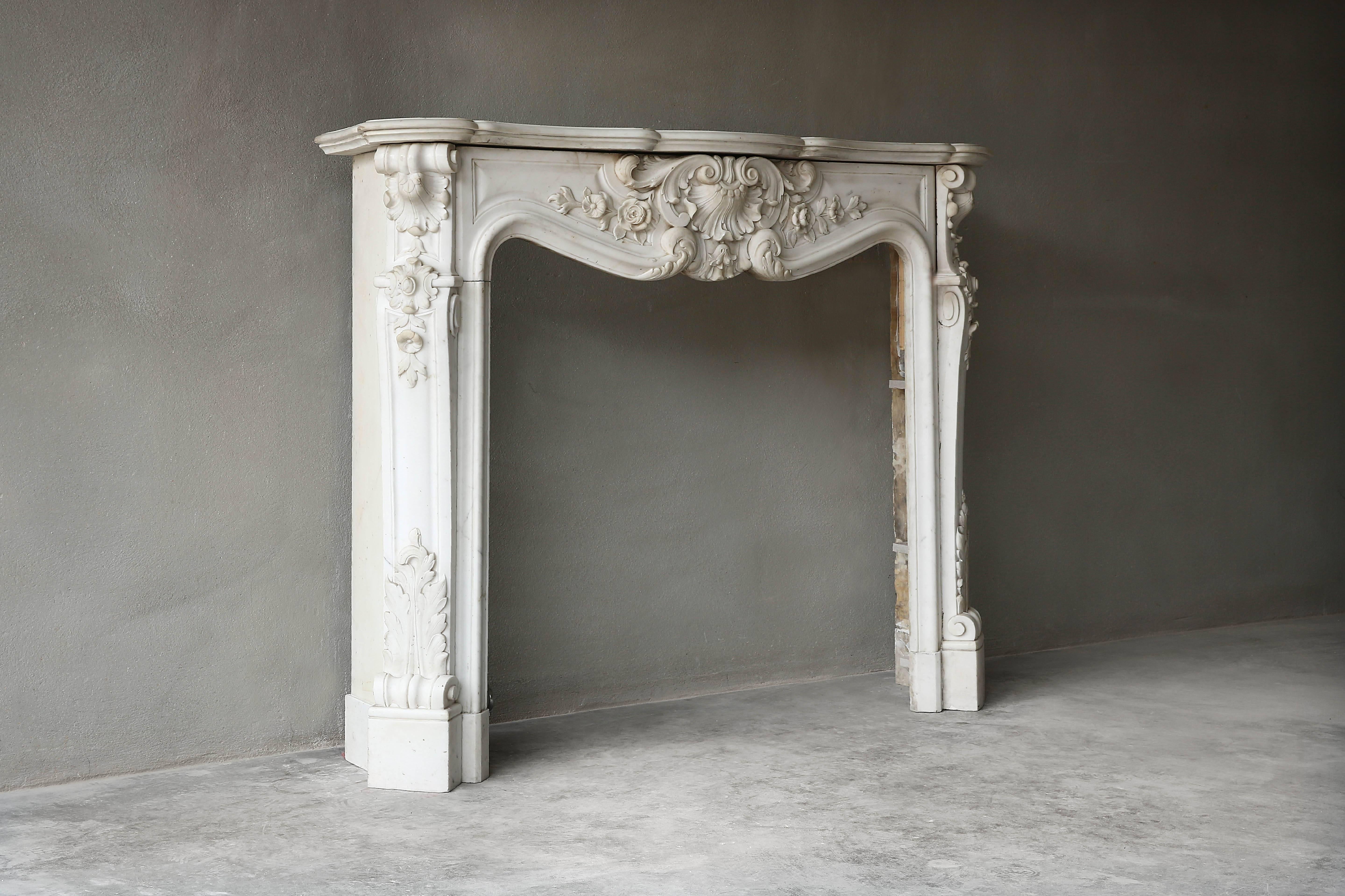 Decorated antique fireplace of white statuario marble in the style of Louis XV from the period 1880-1910. The artist Michelangelo regularly visited the Italian village of Carrara to get this pure white marble out of the quarries and make beautiful