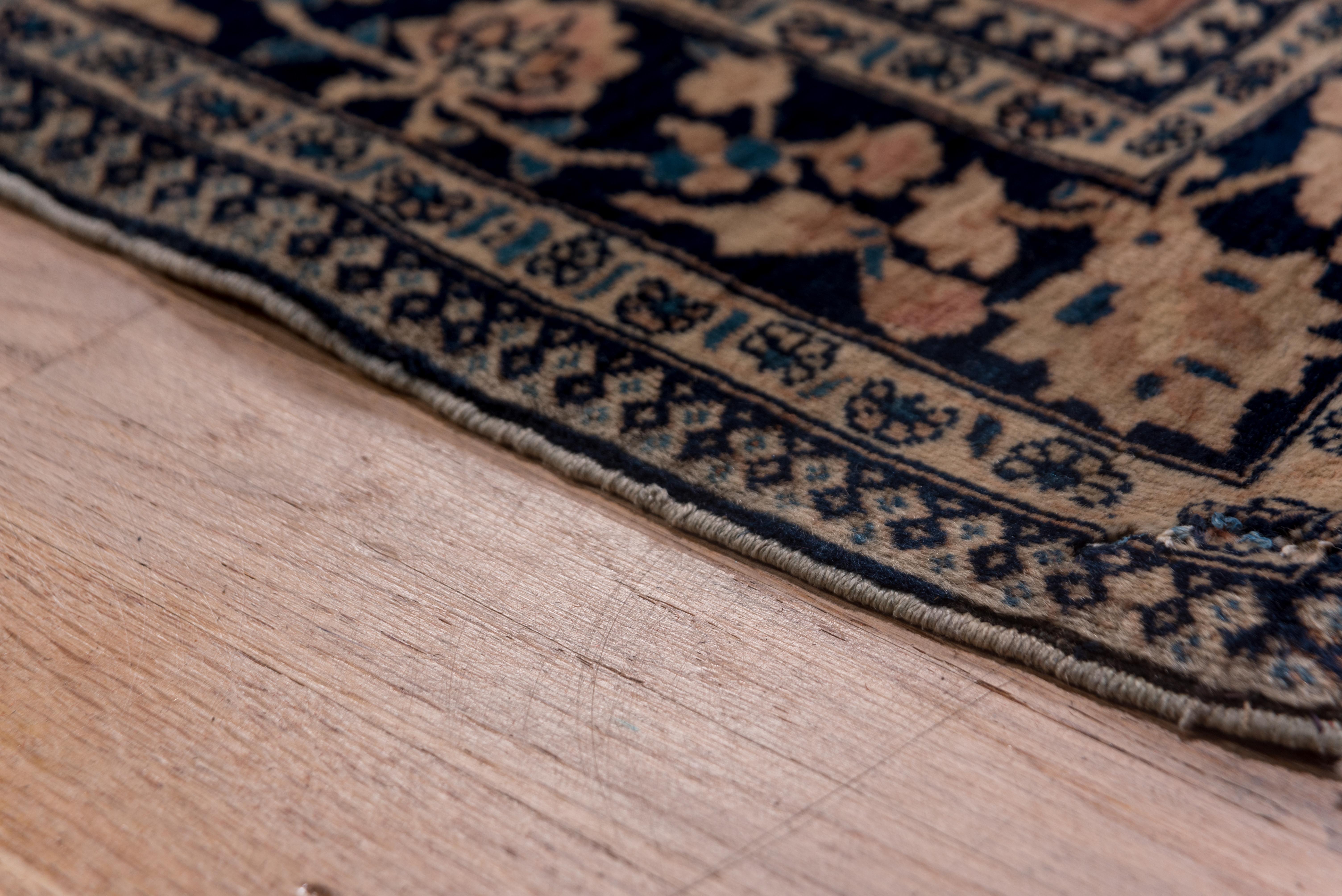 This rare mansion-sized central Persian city carpet in good condition features a navy field filled with actively curling floral tendrils, supporting a layered rose and sand pendanted medallion, strongly accented with cerulean blue spiral vinery.