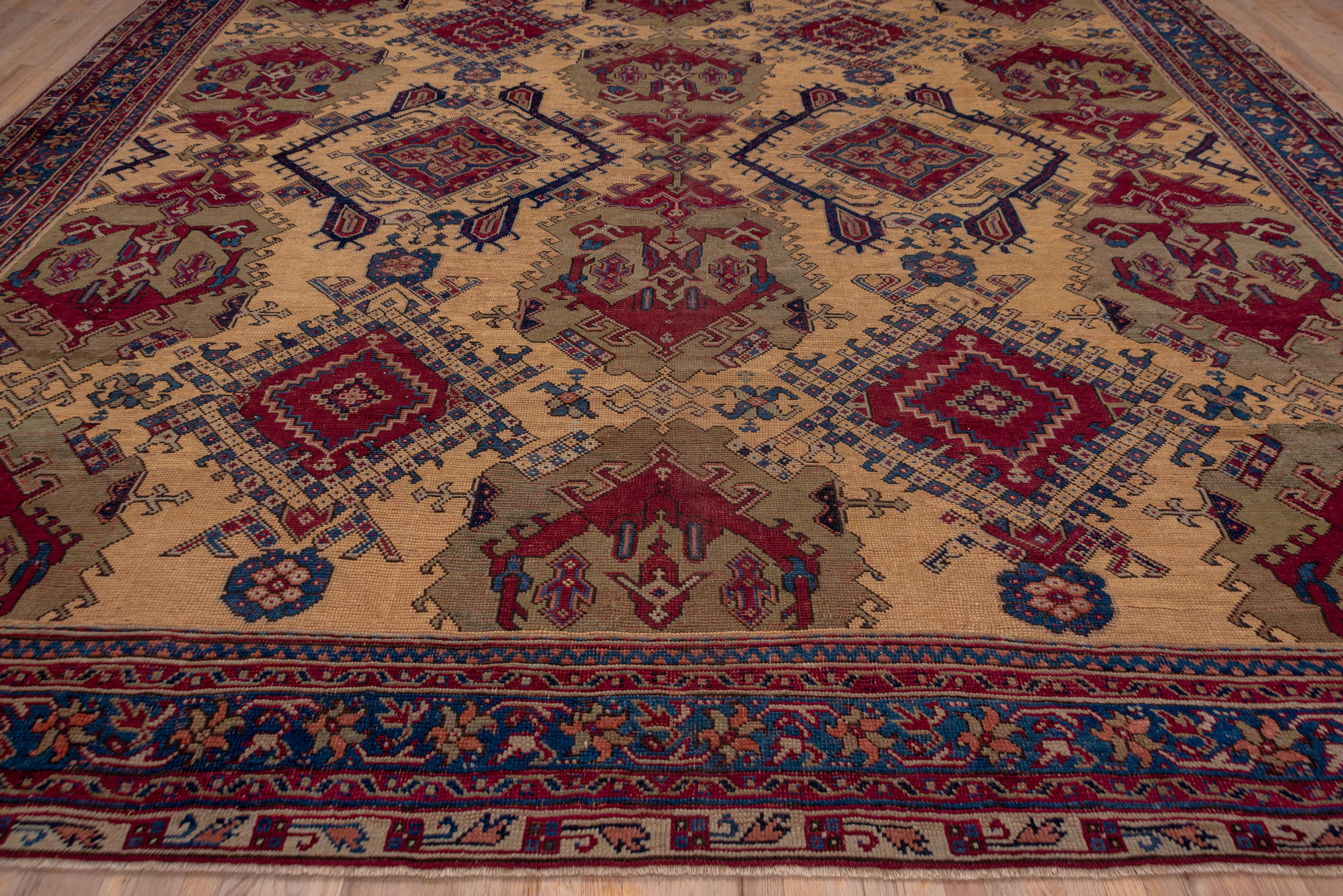 This unusual western Turkish workshop carpet displays five columns of giant hooked palmettes, and Yaprak and color sampler diamonds on an old ivory field with jade green and Turkey red accents. The forest green border presents a vine and tilted