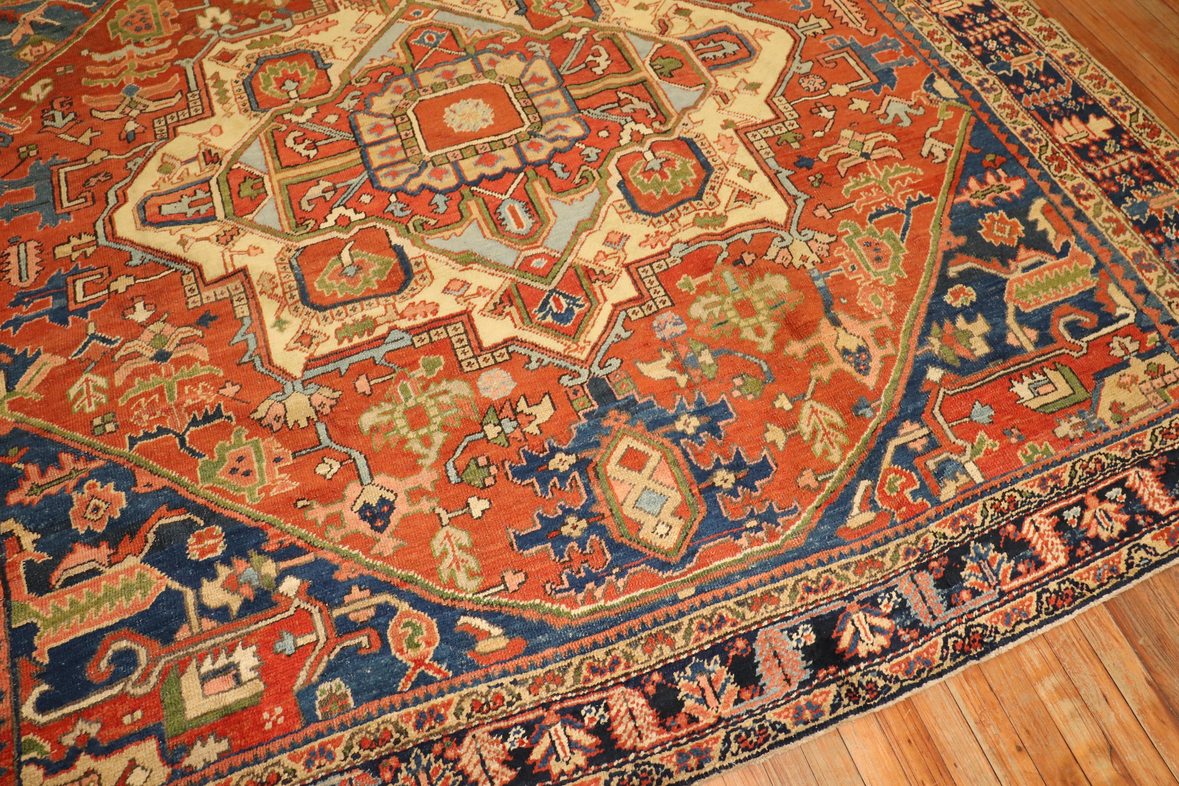 Rare square size traditional antique Persian Heriz rug. Orange field, navy border, Ivory Medallion French Blue corner Spandrels. The Medallion is off center which looks to be intentionally done by the weaver to give it more of a dramatic field. They