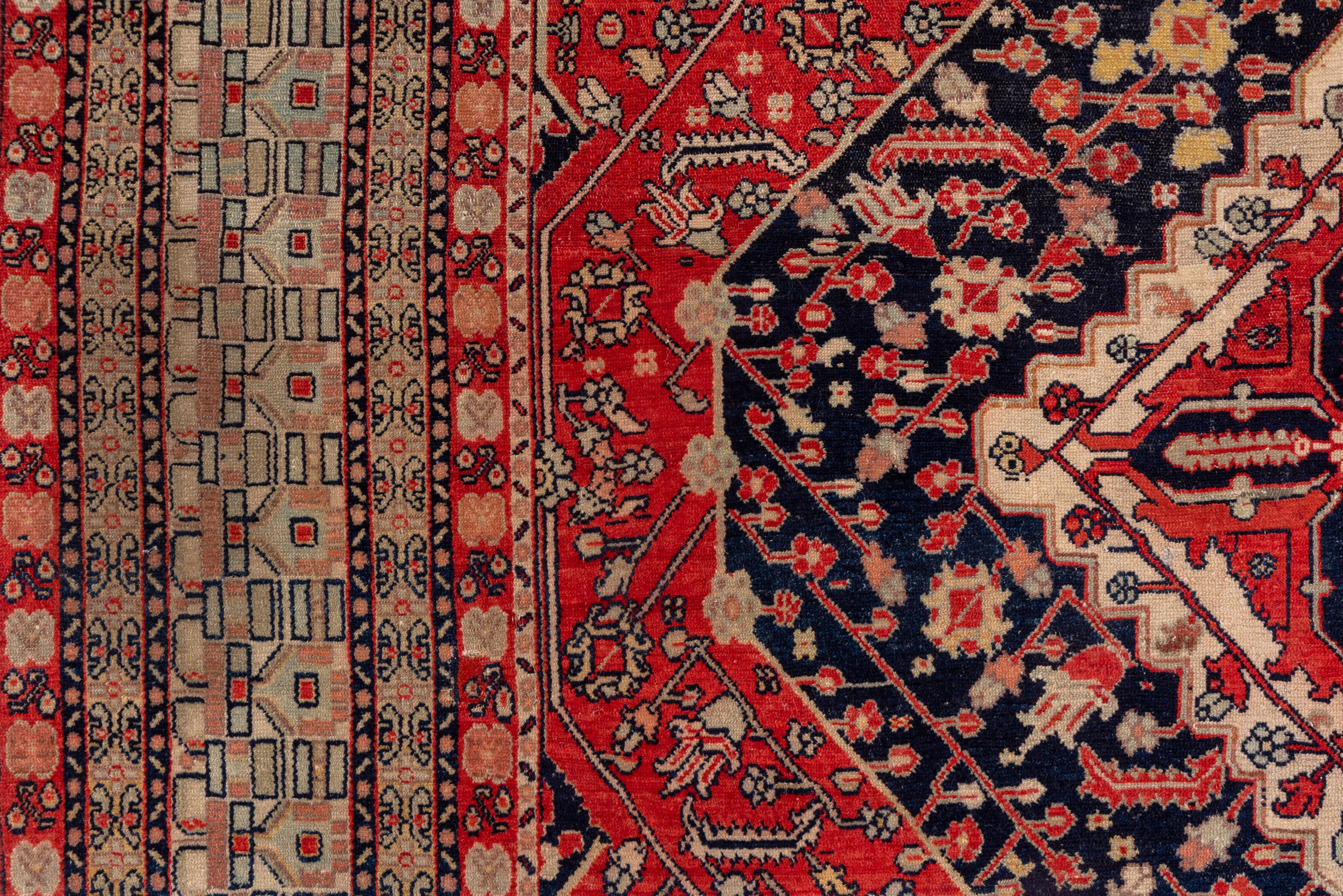 This is a very rare finely woven Kurdish town rug copying a contemporaneous Mohtasham Kashan, with a navy, red and ivory layered medallion set on a rust-red field with a conforming lozenge line and floral pattern, and en suite navy corners with