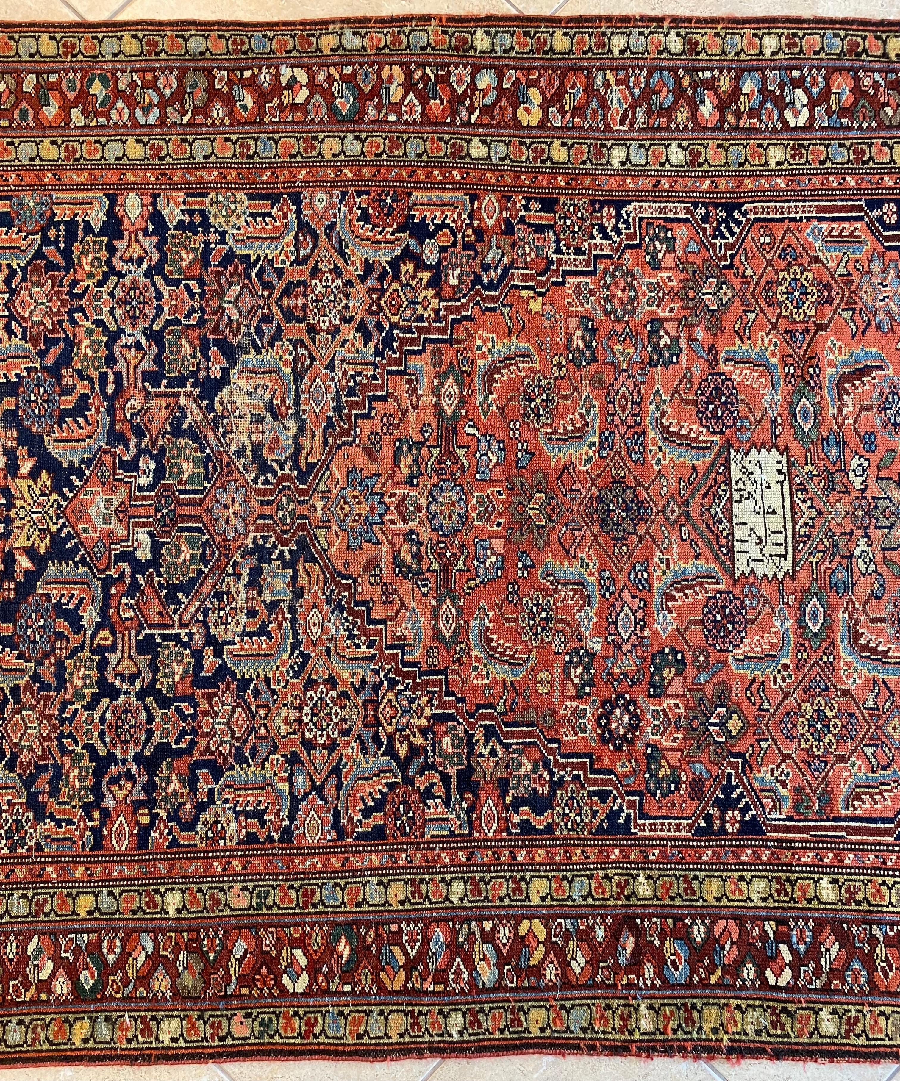 This captivating antique hand-knotted wool runner rug, possibly woven in the late 19th or early 20th century, showcases the enduring artistry of traditional rug-making. The central medallion design in rich rust and blue tones is complemented by