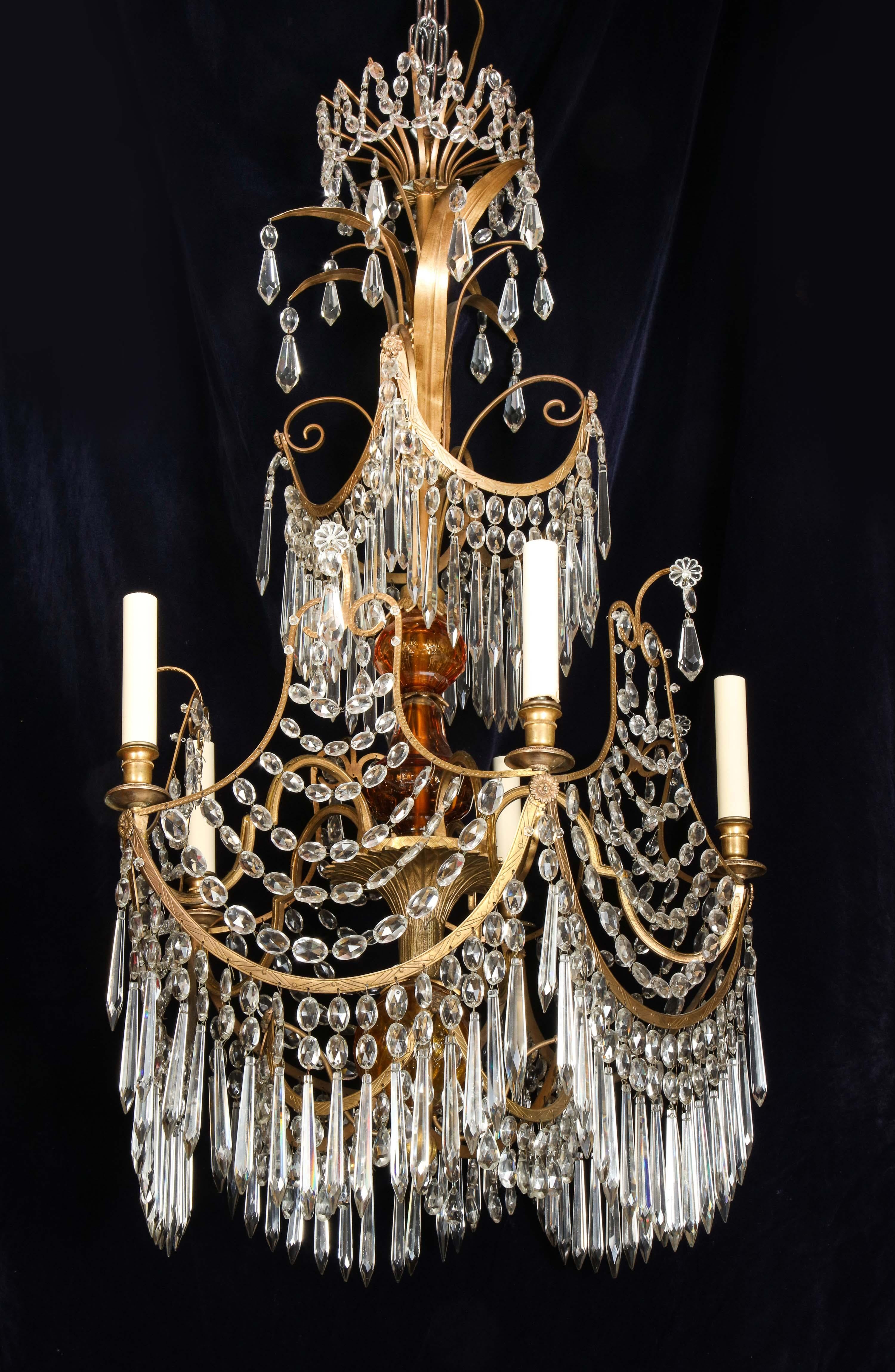 Un rare lustre néoclassique russe ancien à plusieurs lumières en bronze doré, verre ambré et cristal taillé, de forme très unique. Ce lustre est de belle facture, embelli par un verre ambré au centre et orné de prismes en cristal taillé, de chaînes