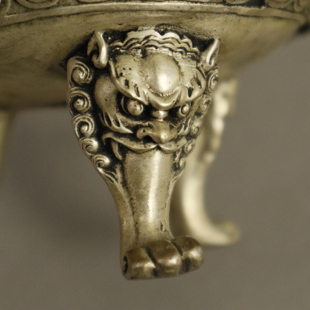 Taza de plata antigua o taza china decorativa, prensada, fundida y cincelada. Pies circulares y curvados con bisagras. 
Decorado con motivos de pavos reales en relieve, nueve animales míticos montados lateralmente y asas de dragón, cuenco esférico