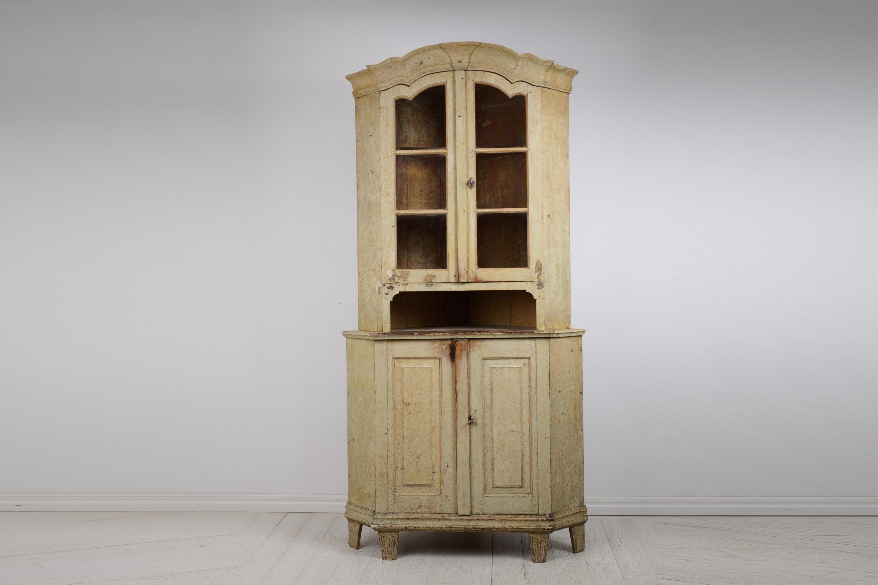 Rare gustavian period corner cabinet with glass doors from Sweden made during the 1790s. The cabinet is made by hand in solid pine into two parts. Made during the transition period between the rococo and gustavian styles which can be seen in the