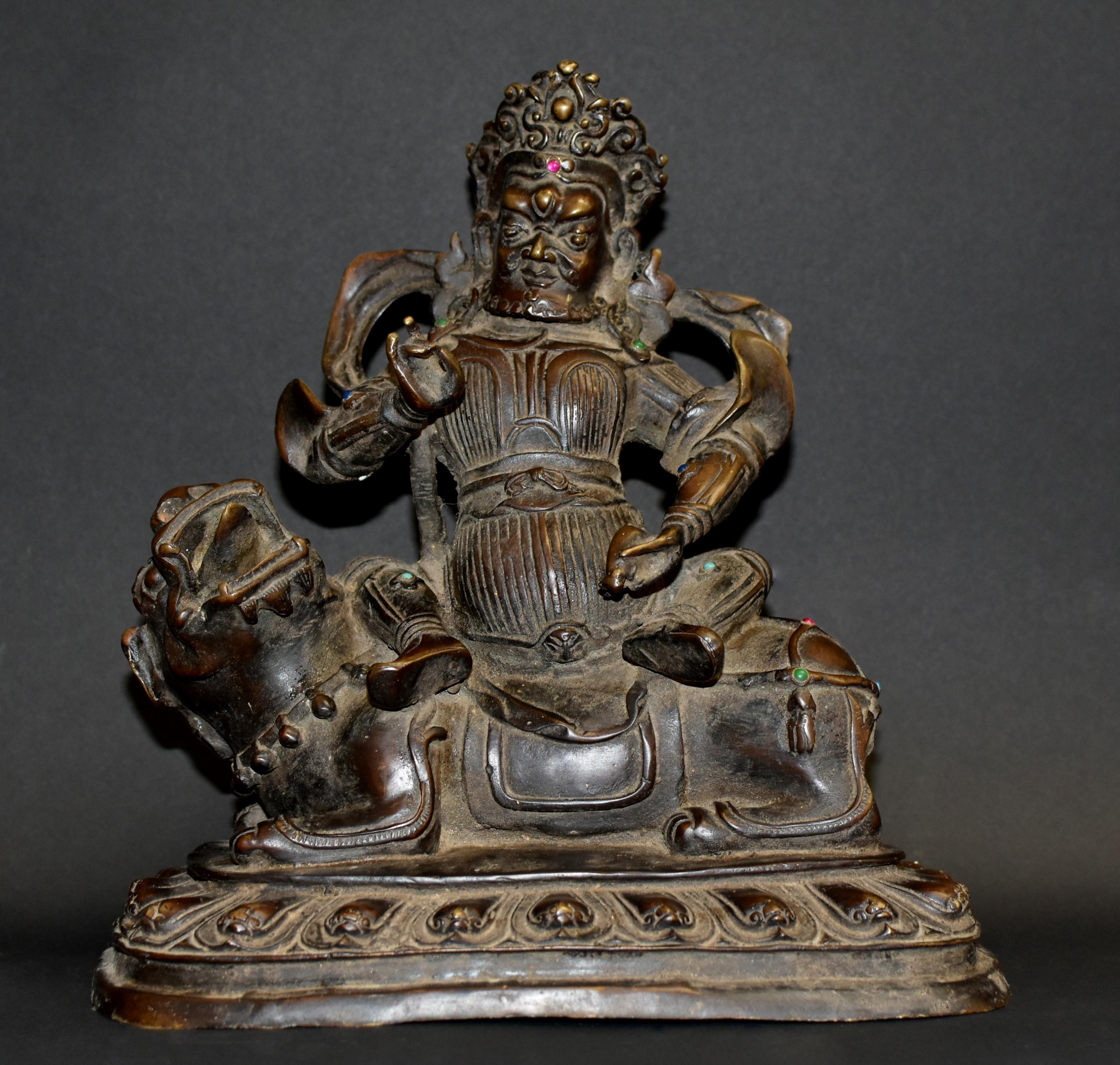 A very rare, 11 lb, fine bronze statue of the Tibetan God of Wealth Kubera. The square face with large protruding eyes has a smiling and benevolent countenance, hair covered in an elaborate crown, dressed in an armor and sits on top of a holy beast,