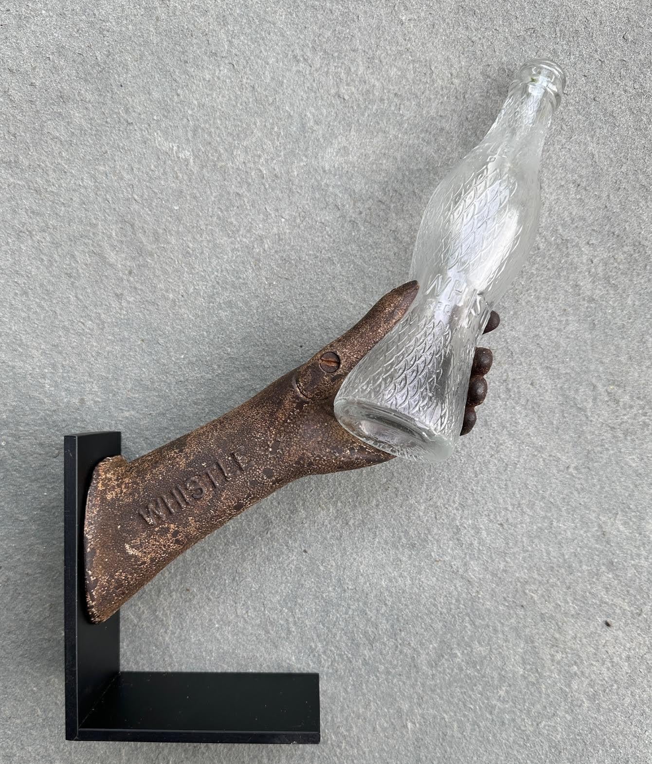 Rare cast iron antique Whistle Soda advertising piece. This figurative shaped hand has a screw off thumb that was made to hold an hourglass shaped bottle of Whistle Soda. This piece comes with an original bottle of Whistle Soda. Originally this