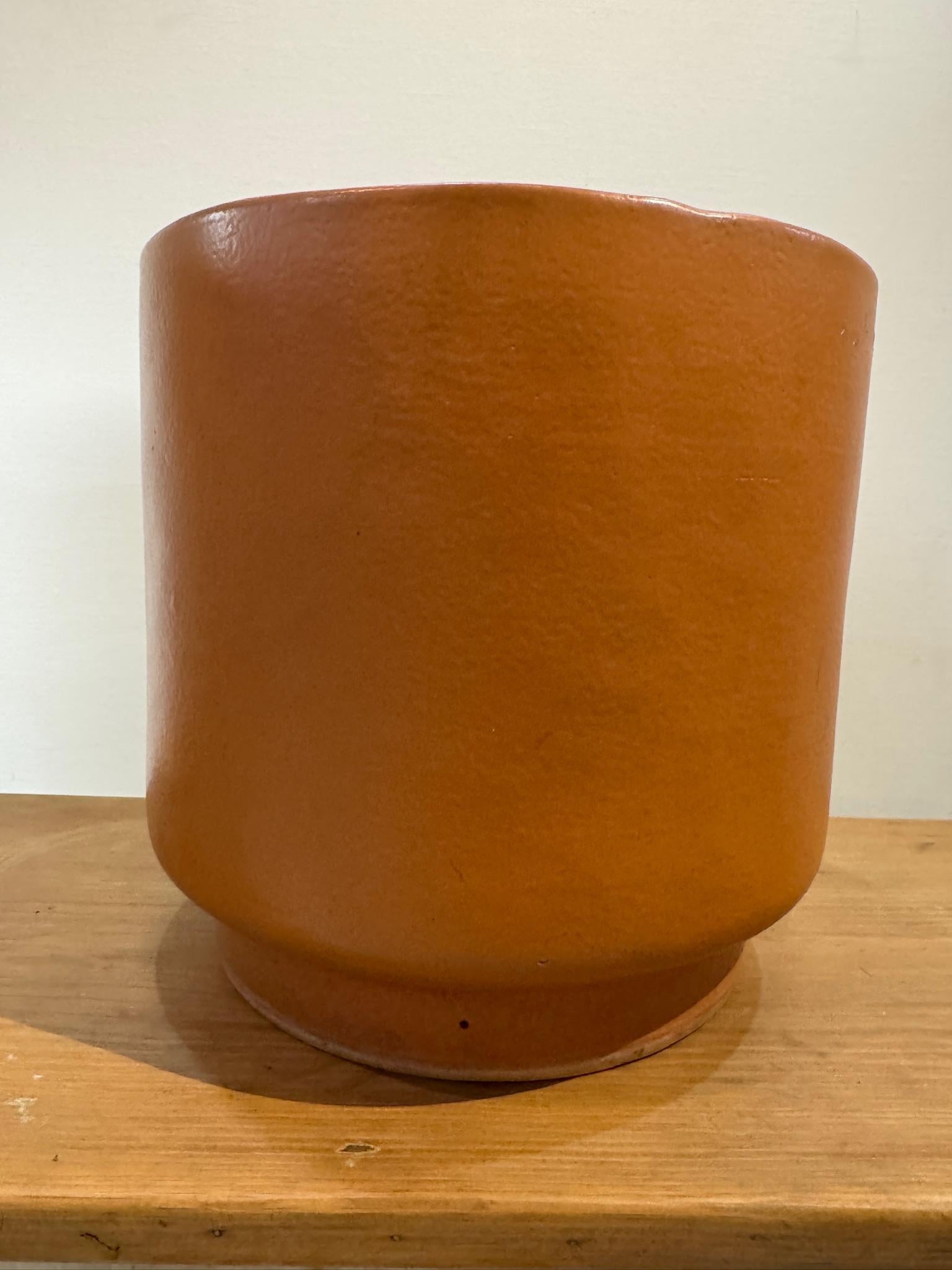 A rare mid-century ceramic planter by Architectural Ceramics of Oakland, CA, not to be confused with the more widely documented Architectural Pottery. Its warm terracotta hue, with subtle earthy undertones, complements its minimalist cylindrical