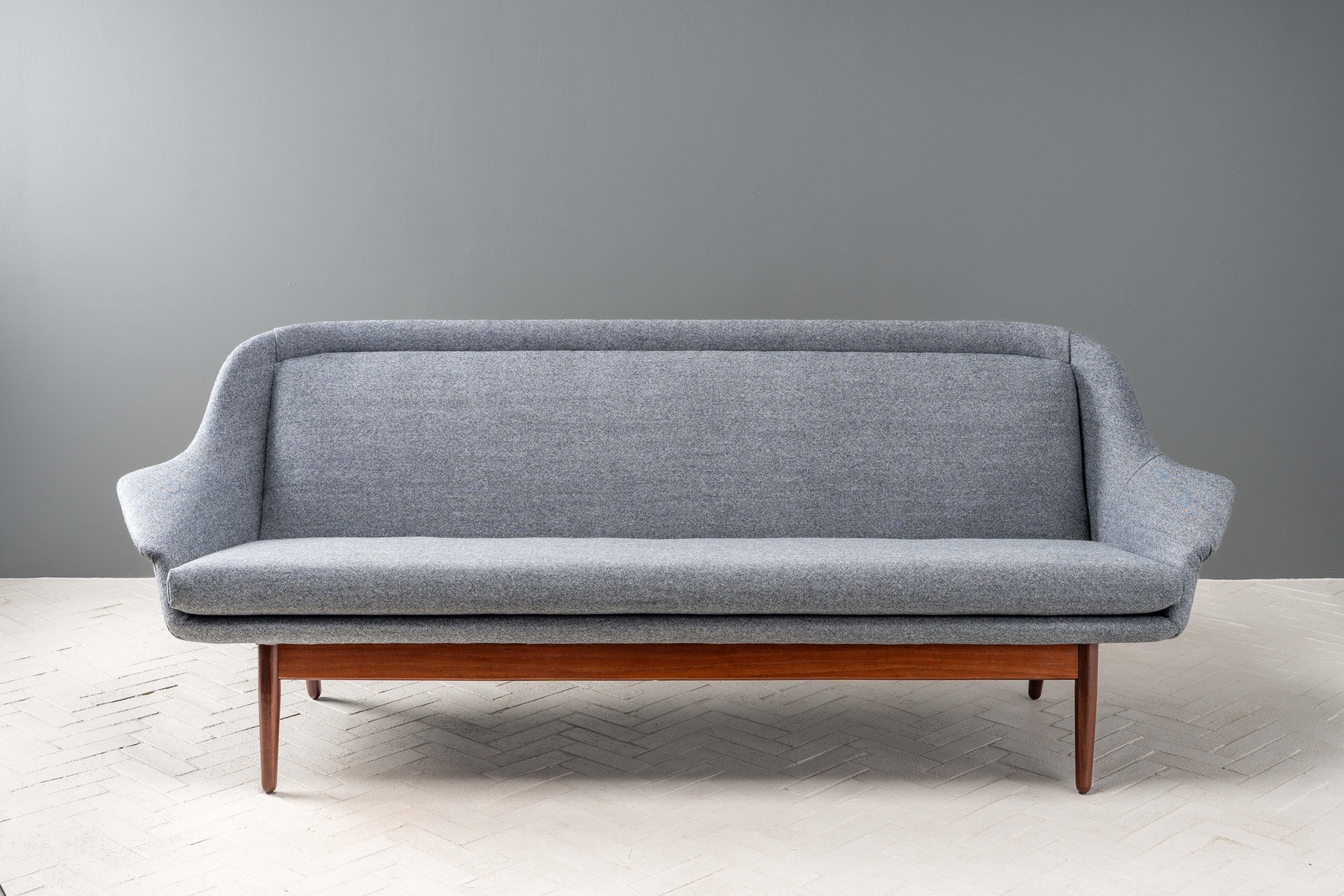 Denmark, ca. 1960s. A rare three-seat sofa by Arne Vodder exclusively for George Tanier. Features attractive sculptural design with flared arms, fixed back, and long reversible bench cushion. Sturdy solid teak base, which has been beautifully