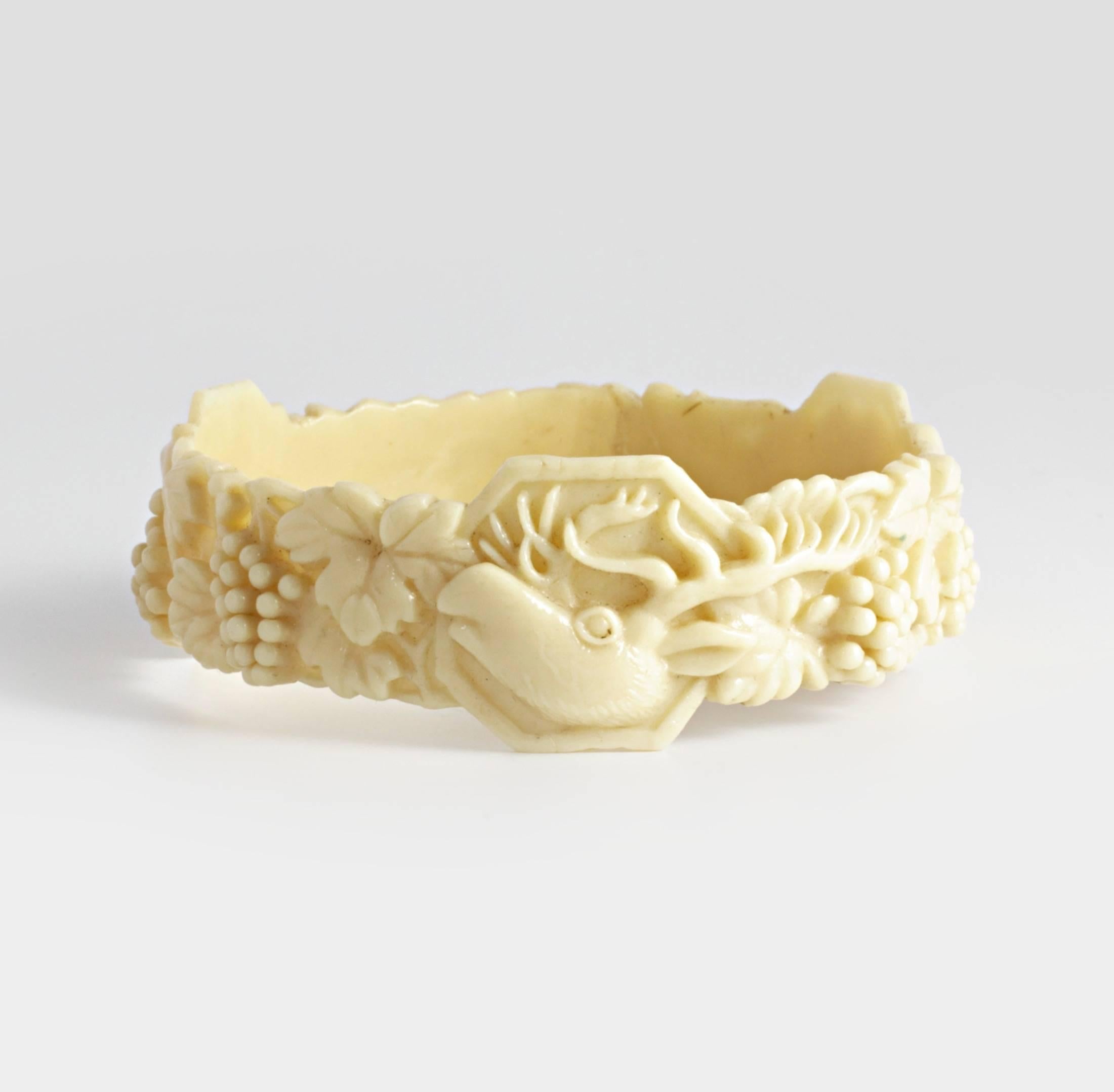 An extremely rare and unusual Ivory coloured celluloid bangle, which depicts three different panels featuring a Stag, an Elephant and a big jungle cat that could be a Leopard or Jaguar, between them, are vine leaves and clusters of grapes. The