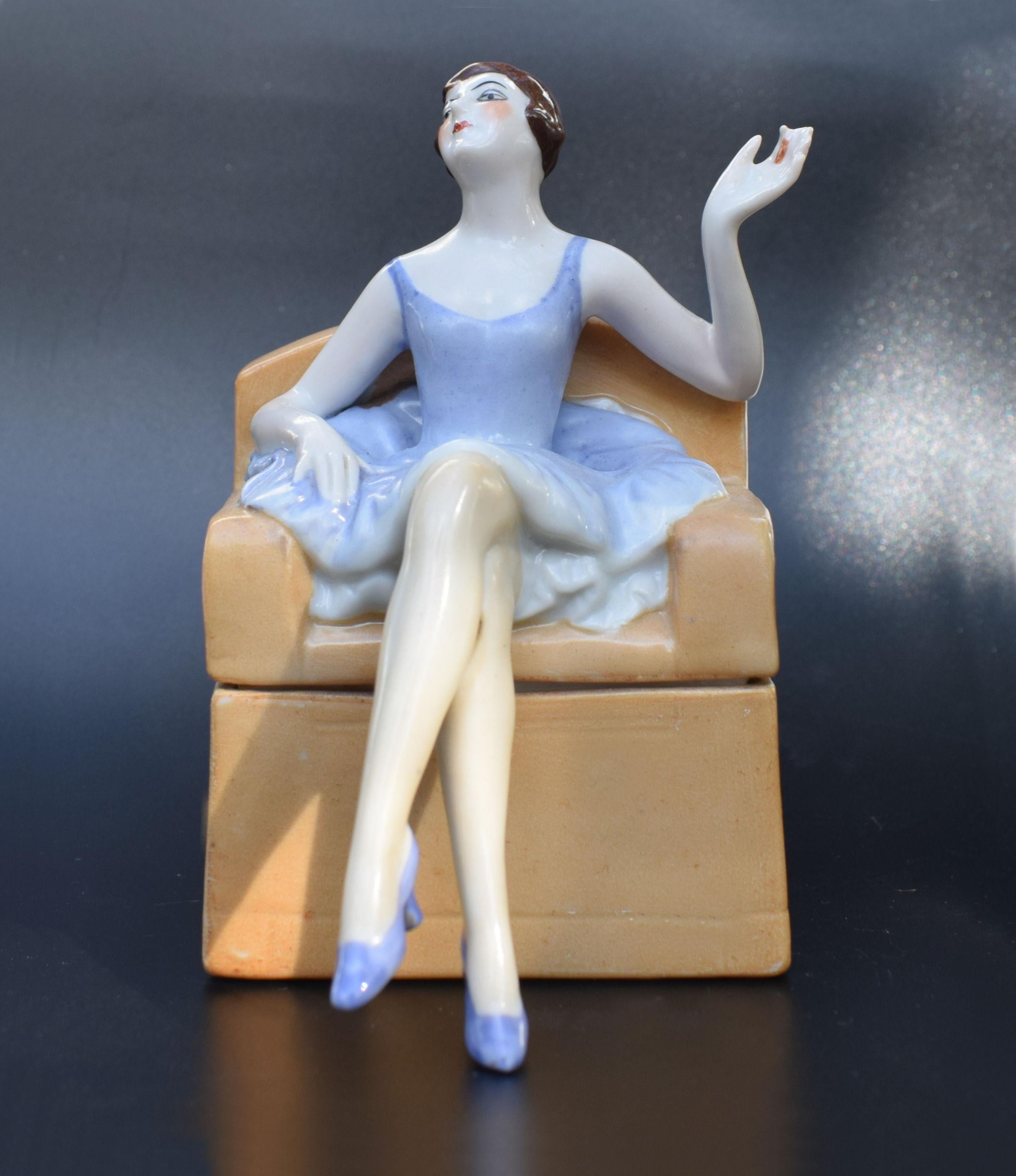 Dating to the 1930s this very attractive and rare Art Deco trinket box is made by FASOLD & STAUCH more commonly known for making half dolls and is a German company. Depicts a flapper girl sat on a legs crossed smoking a cigarette, marked numbers to
