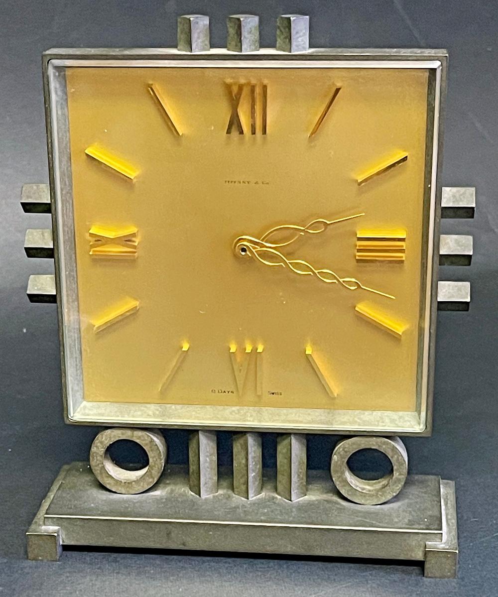 Boldly designed and rare -- perhaps unique -- this extremely fine desk clock by Tiffany & Company consists of a bronze case inset with an 8-day windup clock in glowing brass, all in beautiful condition. The case consists of two o-shaped supports