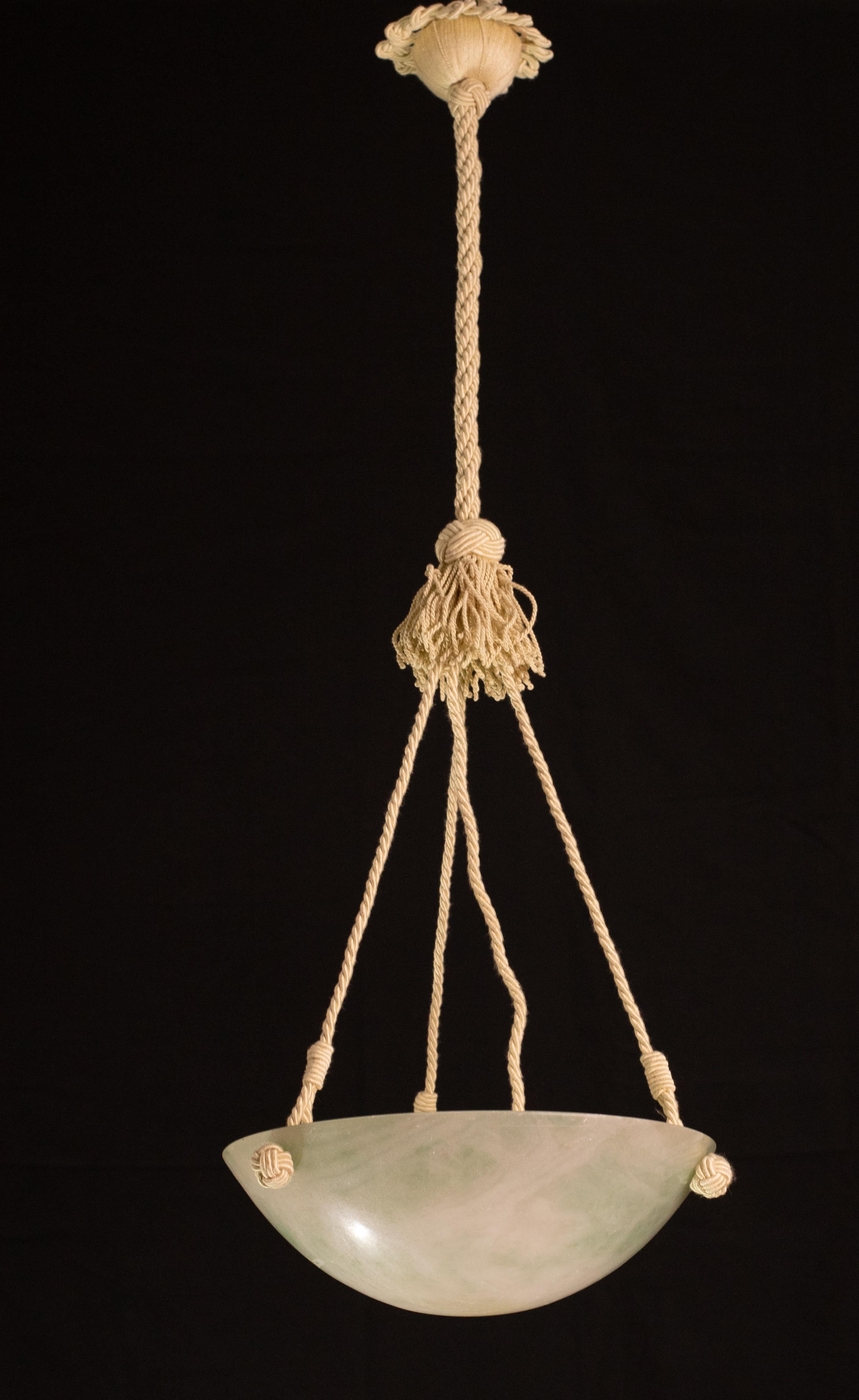 Antique alabaster hanging lamp in Art Deco style, circa 1940s, in rare green stone.
A single piece of alabaster, beautifully worked with hues and reflections of other colours when lit, suspended from three fabric ropes.
The stone is original