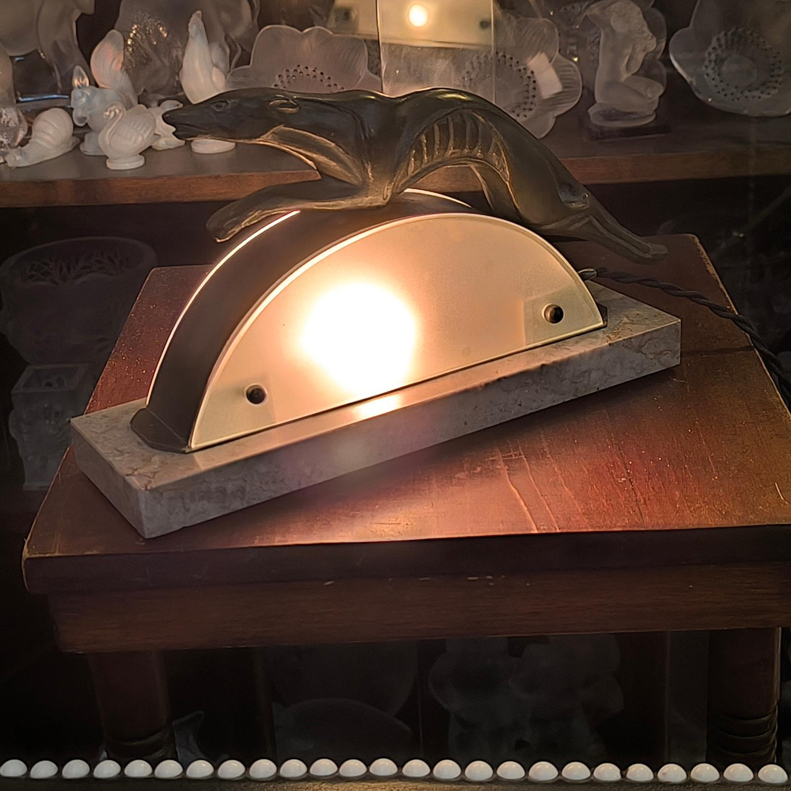 Rare Art Deco Leaping Greyhound Table Lamp, France, 1930s.
A very stylish art deco spelter lamp, depicting a leaping greyhound - the bronze patinated stylized metal greyhounds leaping over a frosted glass arc, mounted on a marble base.
Dimensions:
