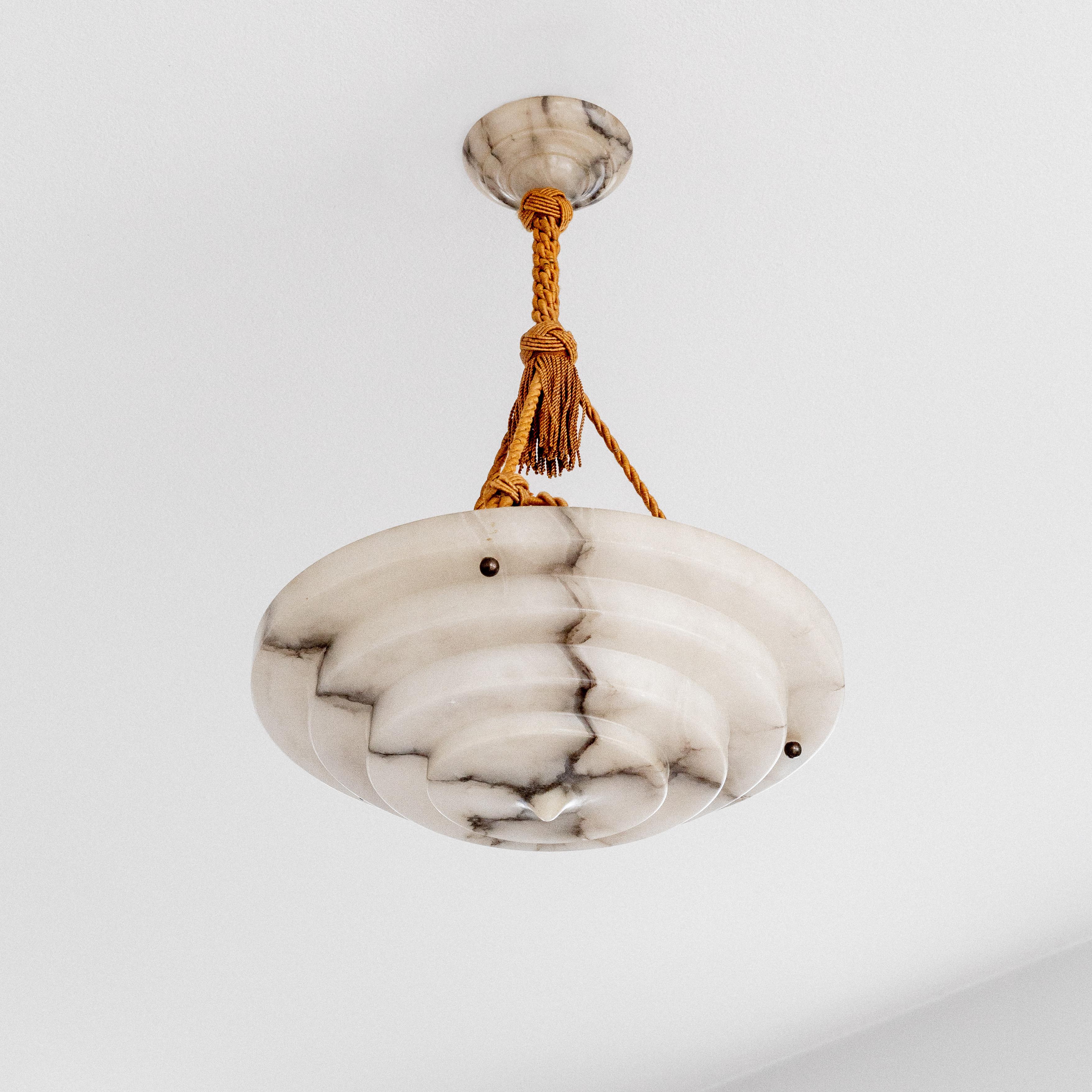 Eccezionale lampada a sospensione svedese in alabastro Art Déco risalente agli anni '20-'30. Questo pezzo di grande impatto presenta un caratteristico design a gradini realizzato in alabastro traslucido con venature naturali che crea una calda luce