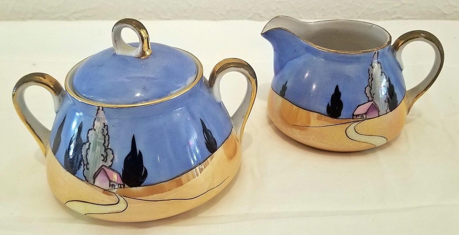 PRESENTE un GORGEUX et EXTREMEMENT RARE crémier et un sucrier à 2 anses et couvercle en Lusterware de Noritake du début du 20ème siècle, période ART DECO.

Belle scène de paysage déco avec maison, arbres, ciel et chemin sinueux.

Vers