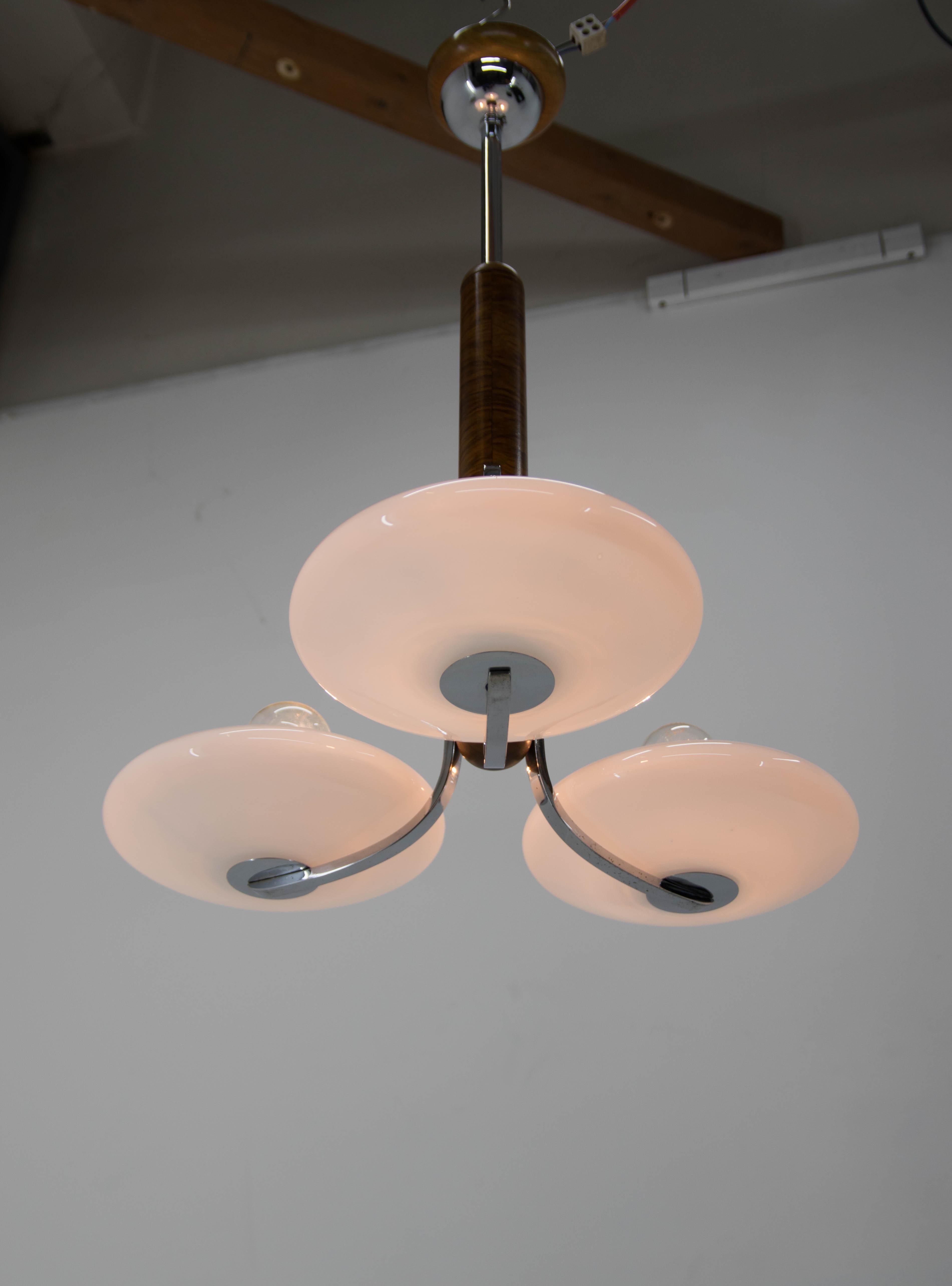 Beautiful and elegant chandelier made by UP Zavody whose main designer was Jindrich Halabala. This rare piece was completely restored: new shellac on walnut rod, chrome polished, rewired: 3x60W, E25-E27 bulb. White opaline glass shades.
US wiring