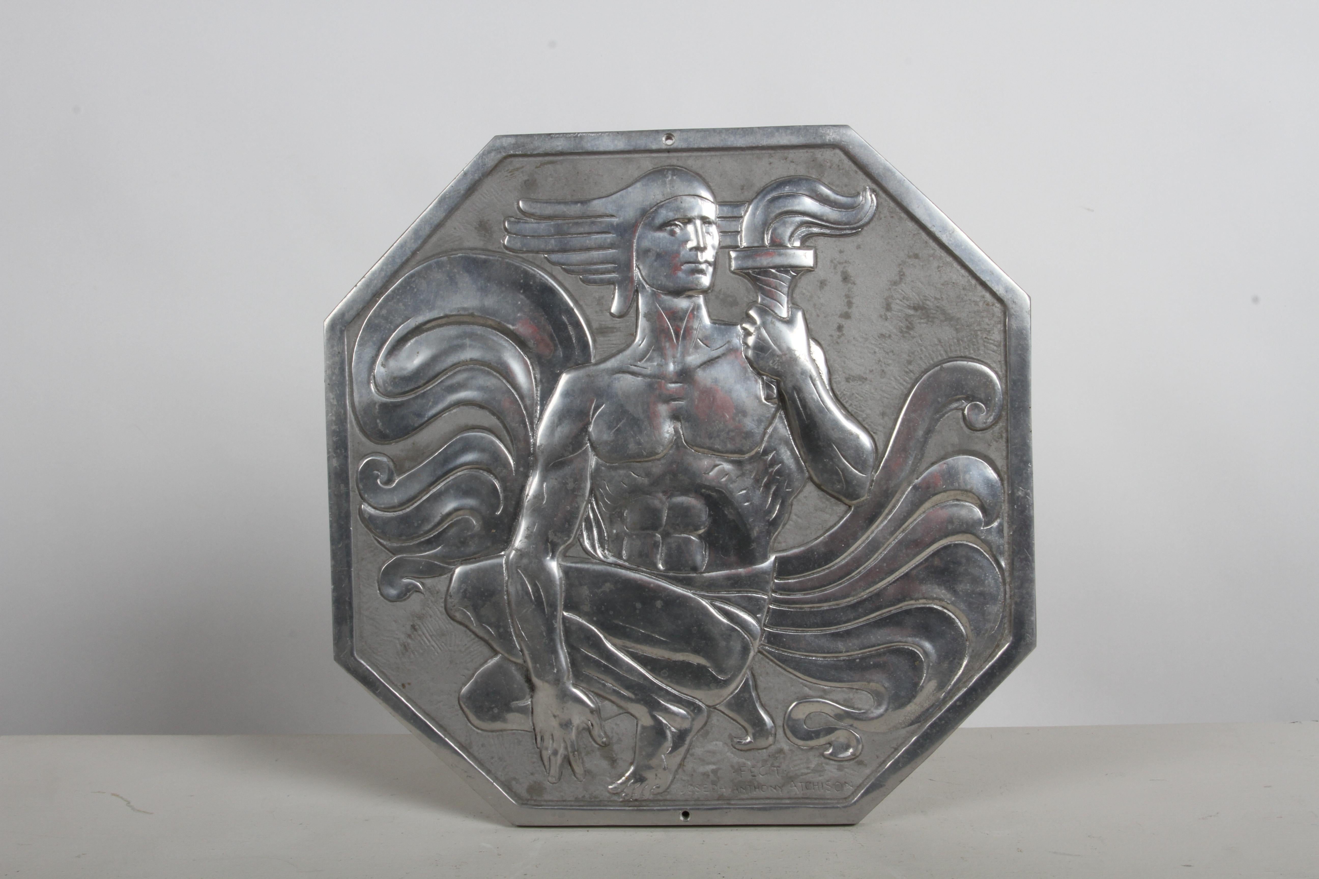 Diese seltene achteckige Relieftafel ist aus Aluminium gegossen und zeigt einen knienden männlichen Akt mit einer Fackel, deren Flamme die wogenden Falten seines Gewandes widerspiegelt. Die Figur trägt einen Helm in griechischer Manier und blickt in