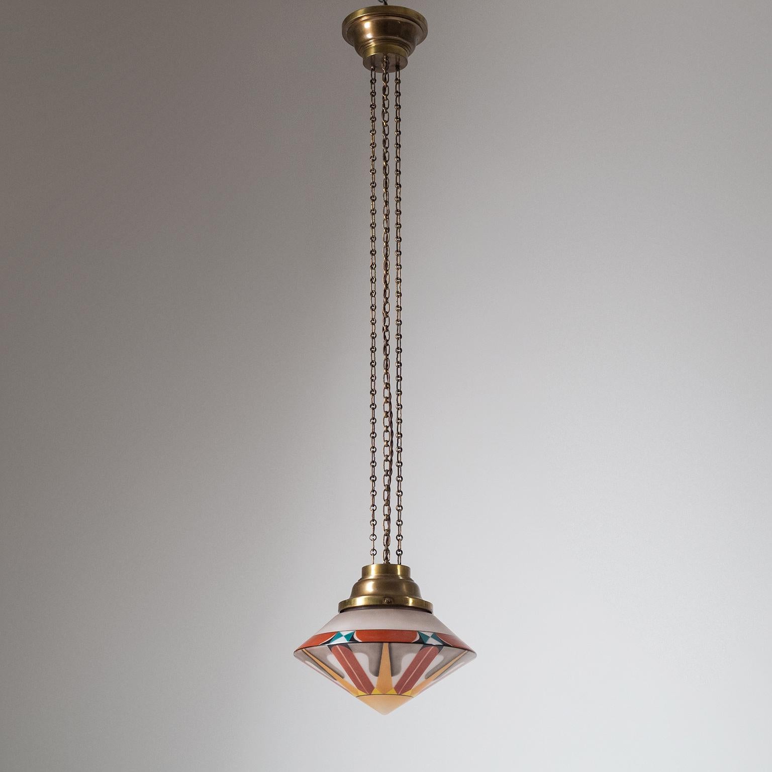 Rare Art Deco suspension light from the 1920s. Large conical blown glass diffuser with a satin finish and multi-color enameled geometric decor. The hardware is entirely in brass with three long chains and symetrical canopy and glass holder. Very