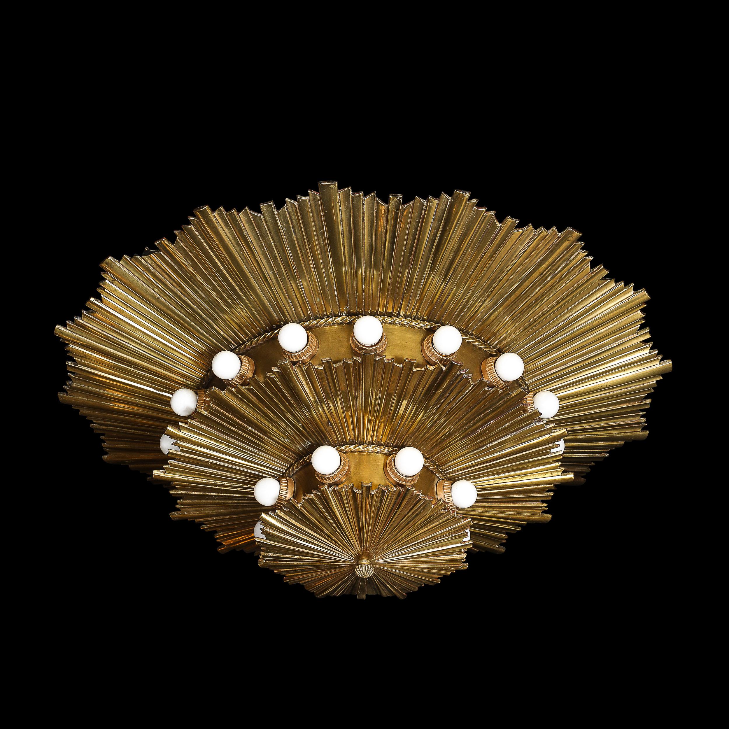This exquisite Art Deco chandelier, crafted in America around 1925, is a masterpiece of design and a testament to the era’s opulence. Featuring a striking three-tier starburst motif in gilt bronze, this flush mount chandelier radiates an