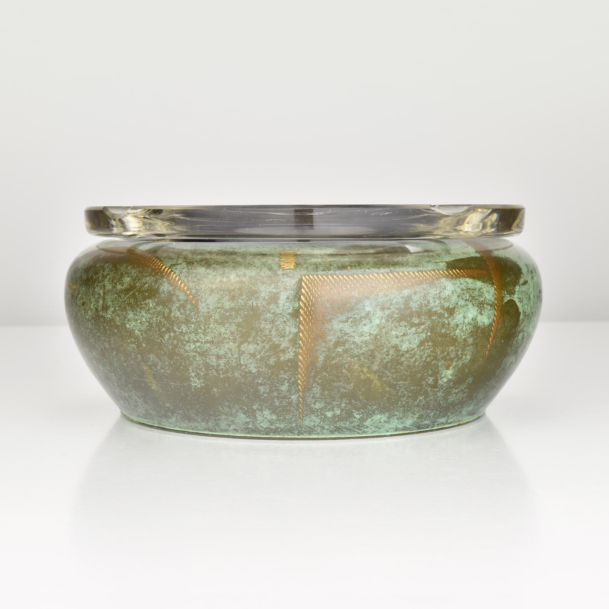 Questo raro posacenere Art Deco di WMF (Württembergische Metallwarenfabrik) fa parte della ricercata linea Ikora, prodotta negli anni Venti. Il pezzo presenta un corpo in ottone patinato con ricche tonalità di verde e bronzo, accentuate da