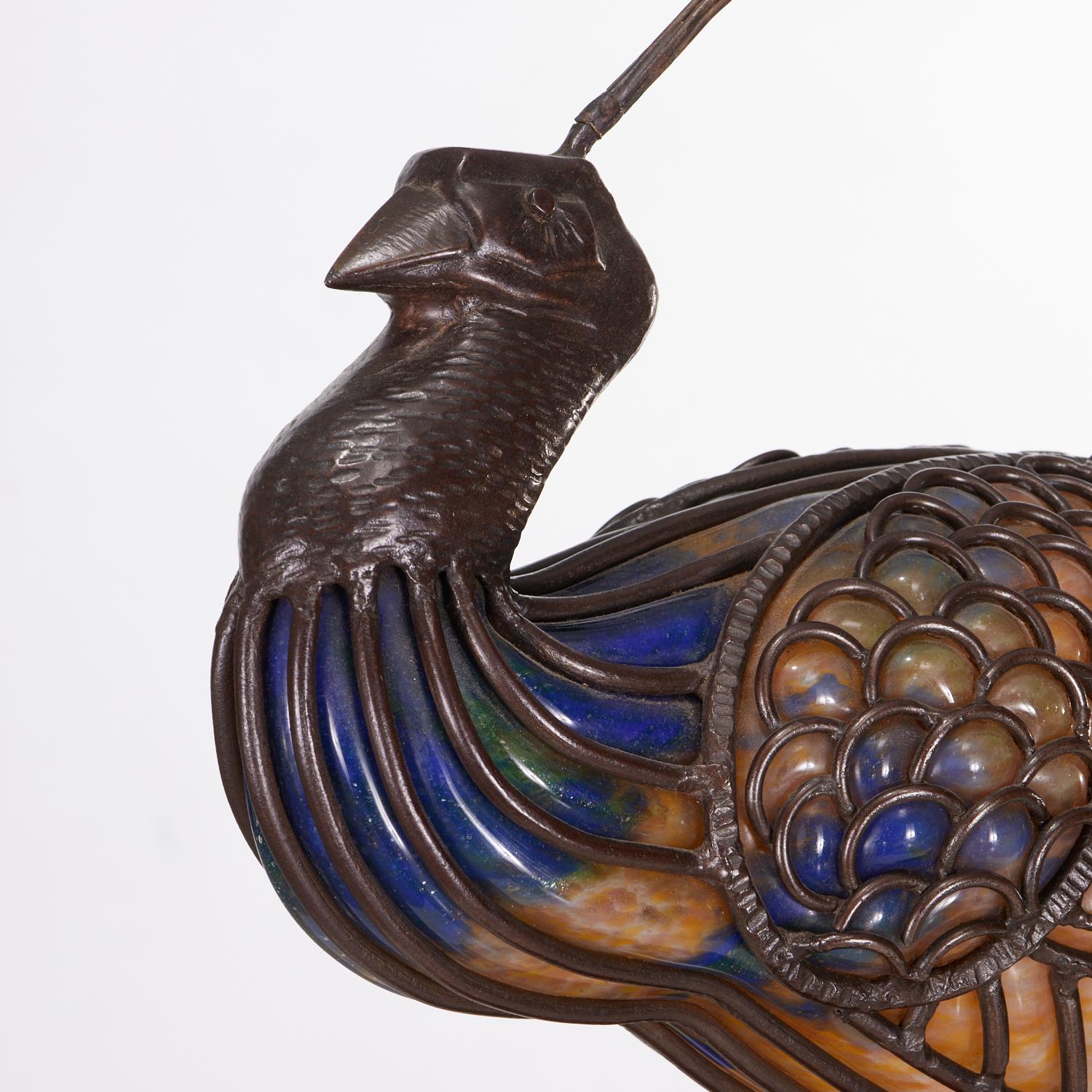 Rare art glass and wrought iron sculptural lamp by Muller-Frères, representing a peacock bird. This sculptural lamp is finely crafted with a brown patinated wrought, hammered iron sculpted bird inset with blown 