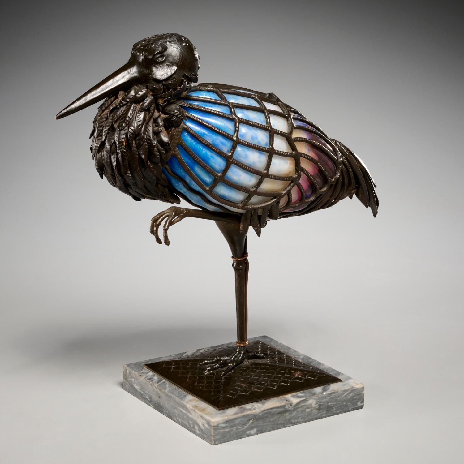 Rare lampe sculpturale en verre d'art et fer forgé de Muller-Frères, représentant un oiseau cigogne debout sur une patte. Cette lampe sculpturale est finement travaillée avec un oiseau sculpté en fer forgé martelé patiné brun, inséré dans un verre