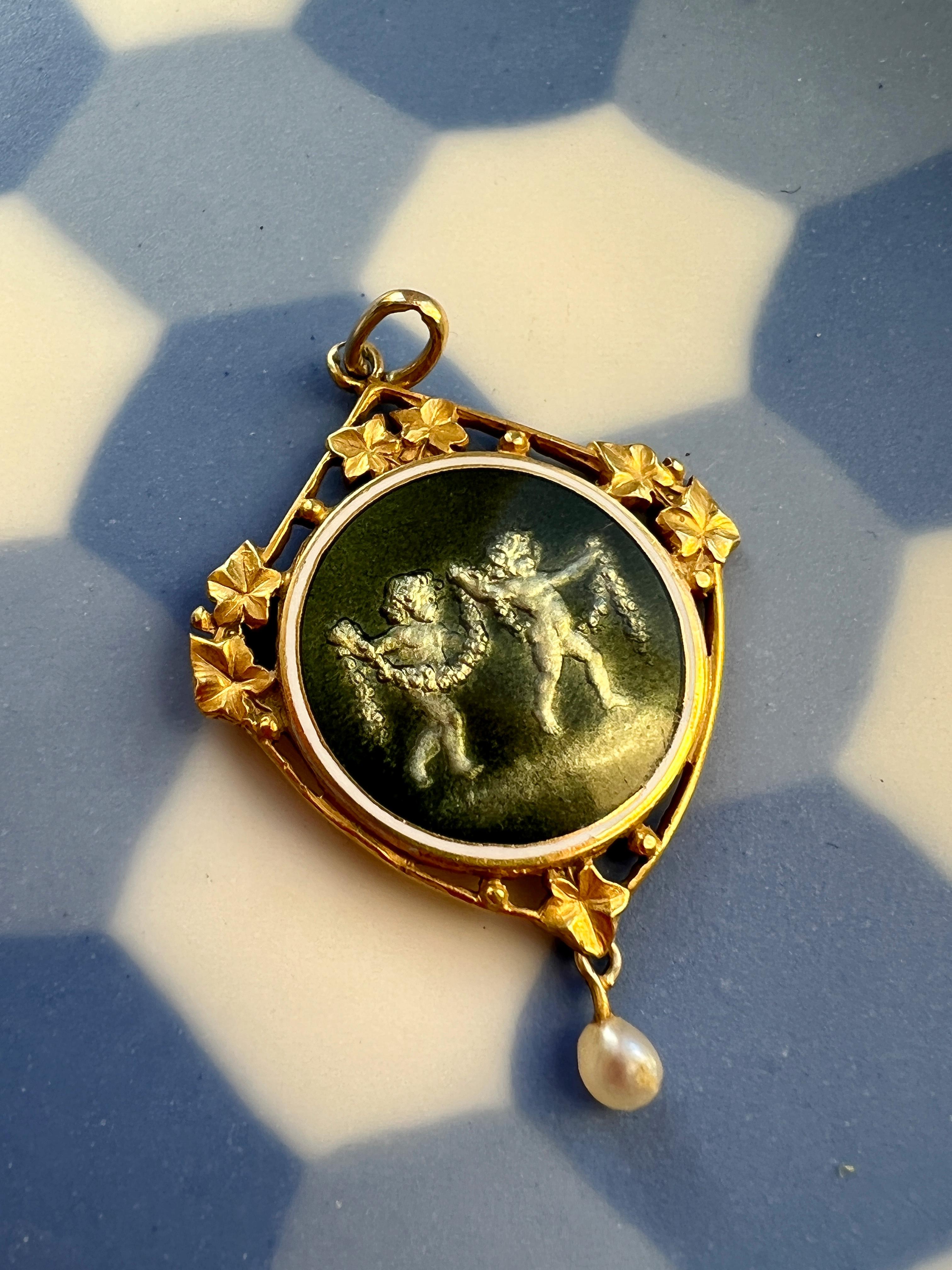 Nous avons devant nous un pendentif médaille en or 18 carats de l'époque Art nouveau, très attrayant et inhabituel, présentant un émail suisse rare aux couleurs métalliques : la couleur passe d'un vert olive à un gris minéral sous différents