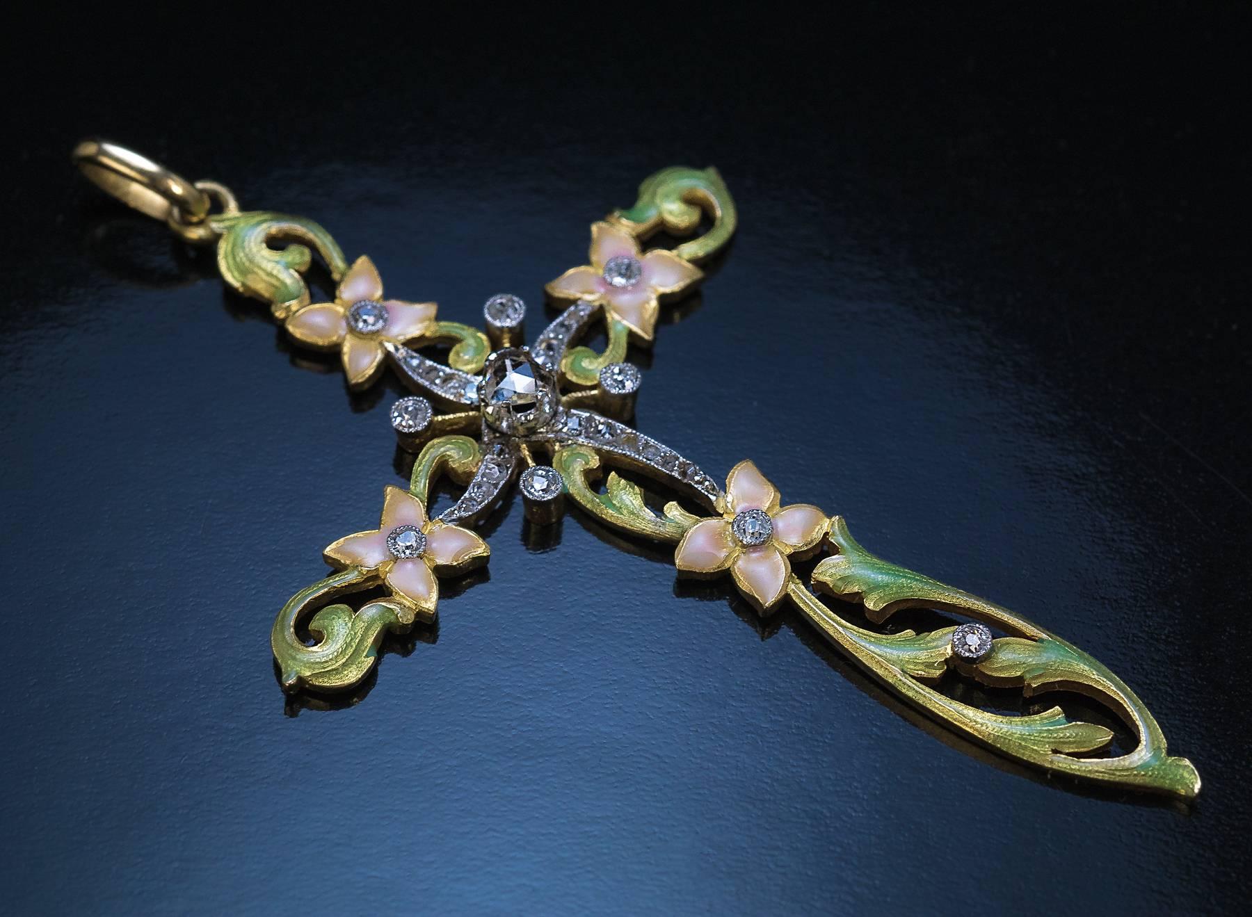 Circa 1910

A superb Art Nouveau 18K gold openwork cross pendant with a diamond-set platinum center.

The front of this large cross is embellished with pastel rose and golden green enamels. The cross is centered with a pear shape rose cut