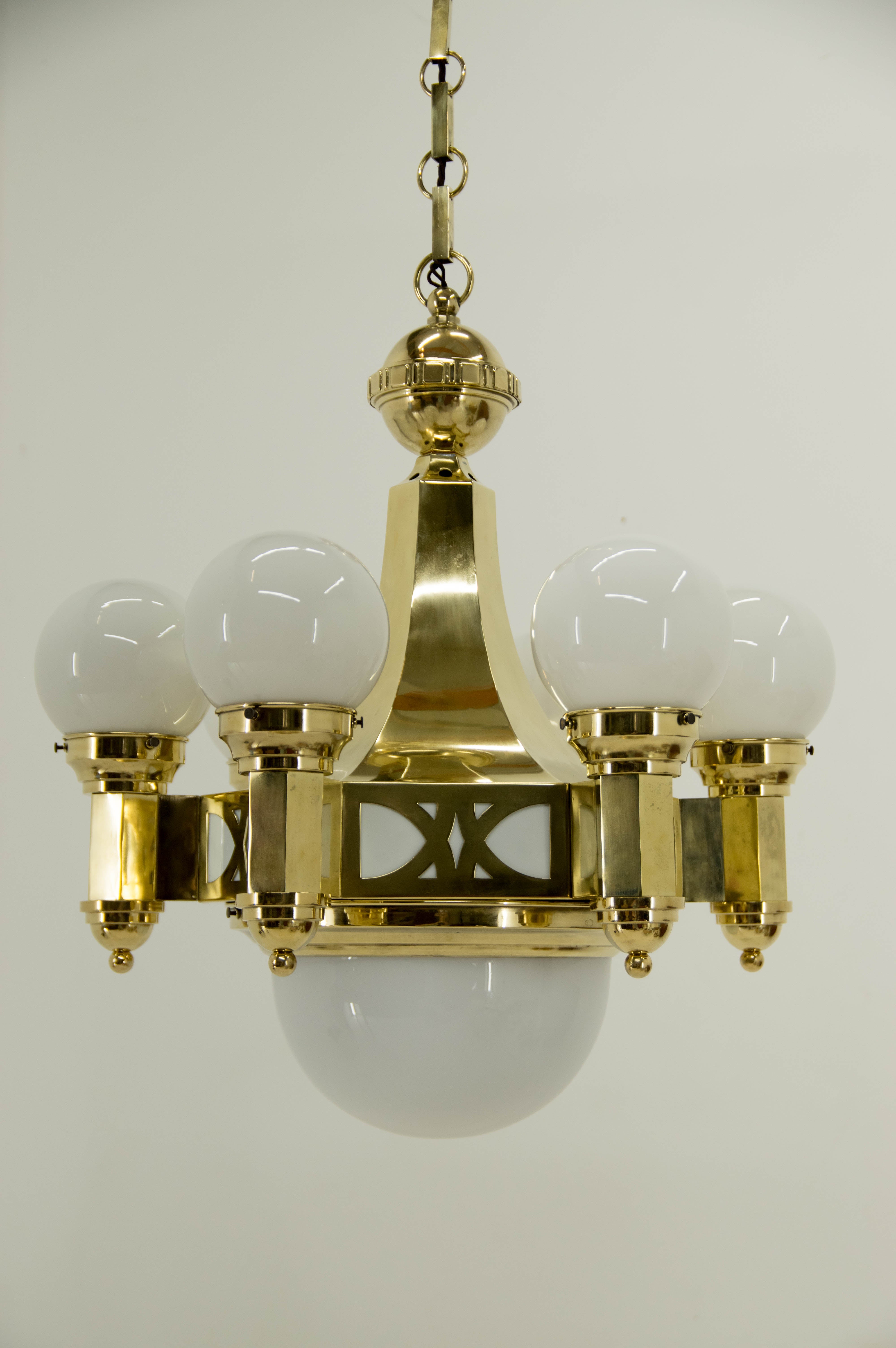 Very rare late Art Nouveau brass chandelier designed by architect Emil Kralik. 
Manufactured in Vulkania Prostejov where Kralik was a director.
Item was completely restored, brass refinished and polished.
One cca 3cm crack on one arm was