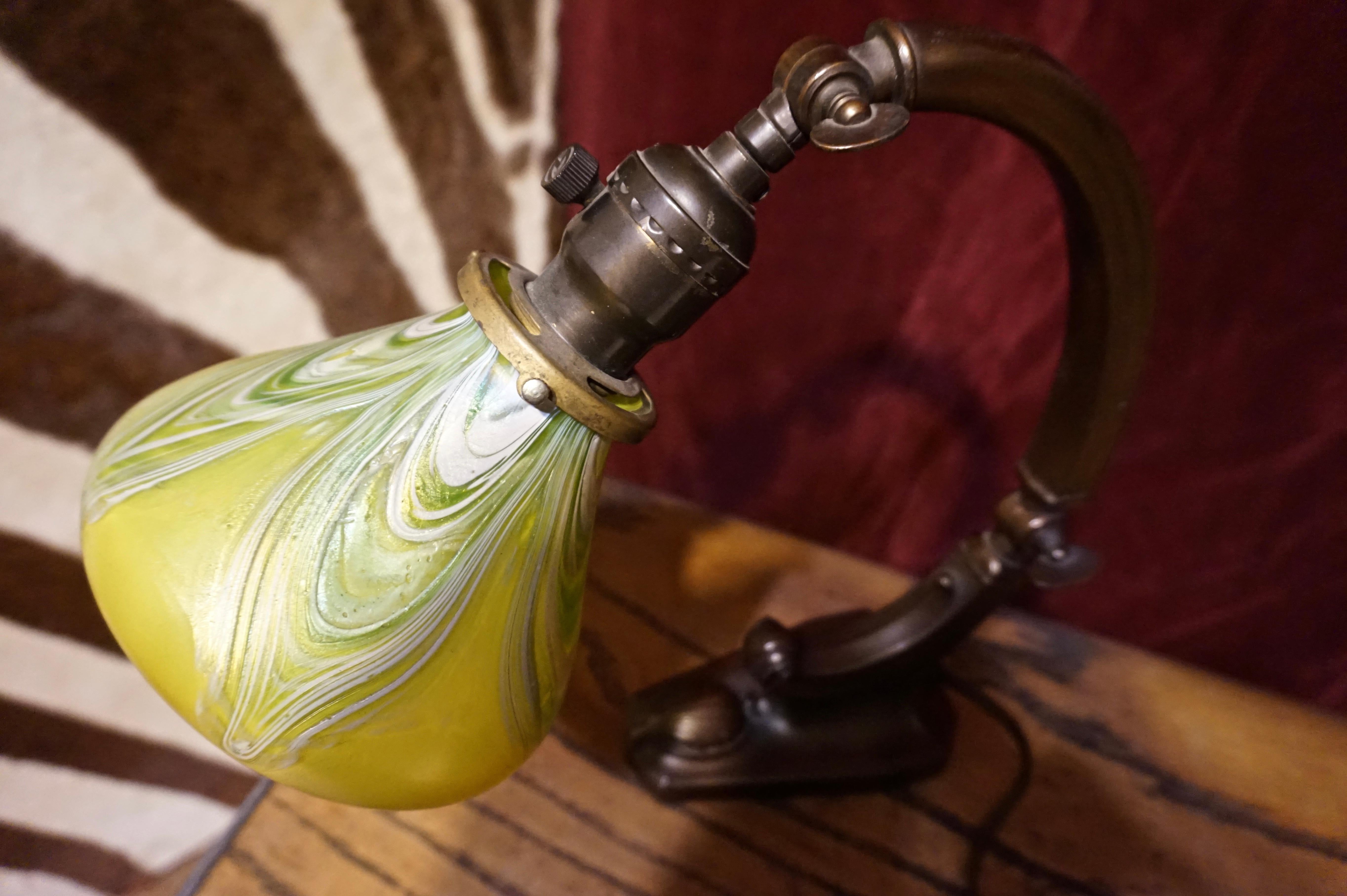 Beautiful Art Nouveau stained glass lamp in working condition. Adjustable, curving brass stem. Throws a warm light while projecting aesthetic perfection. In the Tiffany style for a fraction of the price. Sturdy.