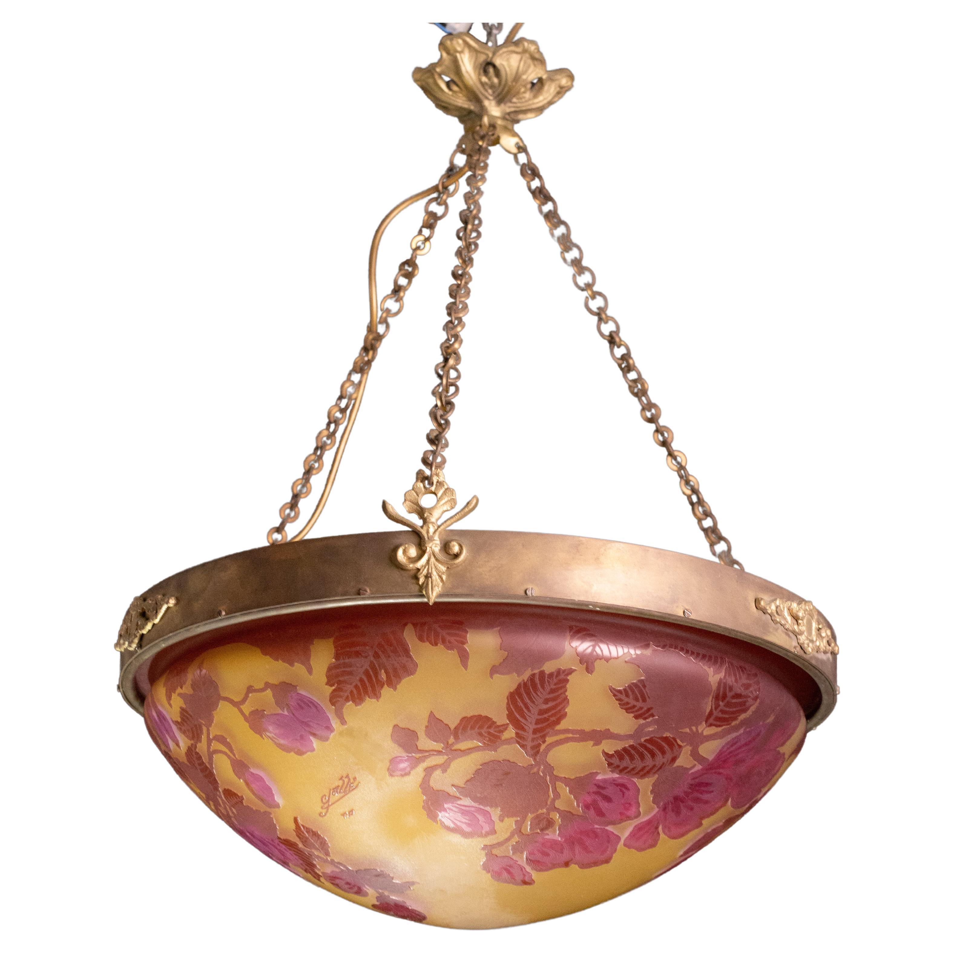 Rare Art Nouveau, Cameo glass and cast bronze chandelier by Émile Gallé. The unusual relief overlay depicts floral patterns on a multicolored background.
A beautiful disk that changes color when lit.
Signed: Gallé. 
Suspended by original cast bronze
