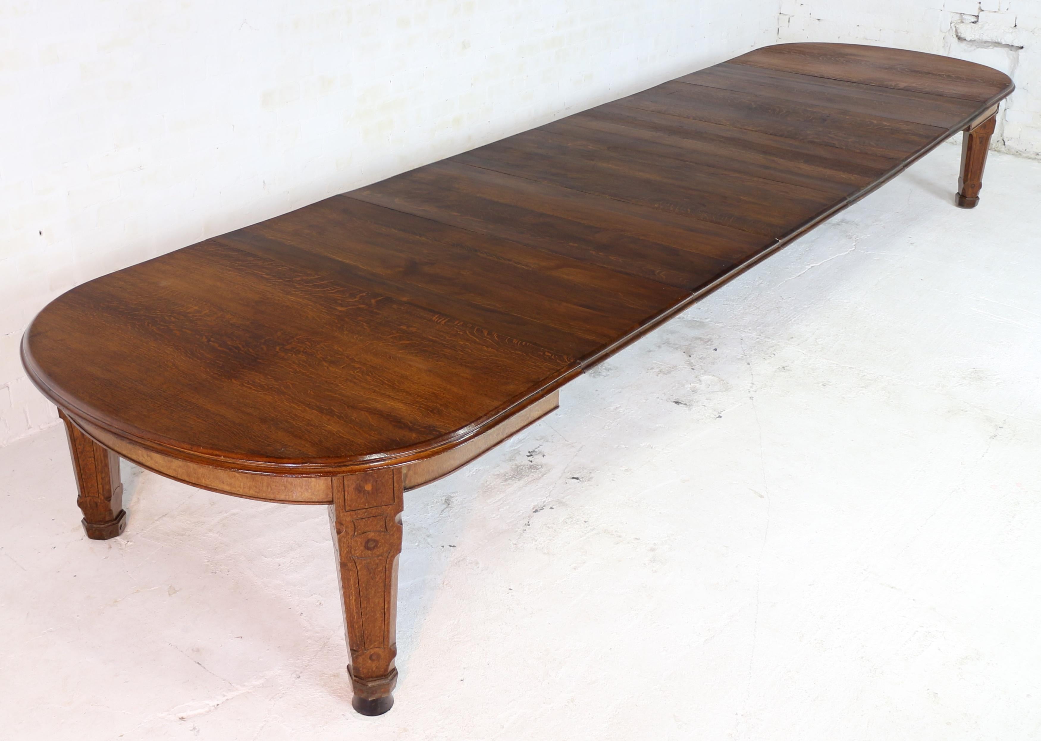 A rare Arts & Crafts inlaid Gothic Revival 18 1/2ft wind-out dining table, probably designed by Charles Bevan and made by Gillows of Lancaster. In quarter-sawn oak and with seven leaves, this large 5ft wide table smoothly extends from 6ft 6.5in to