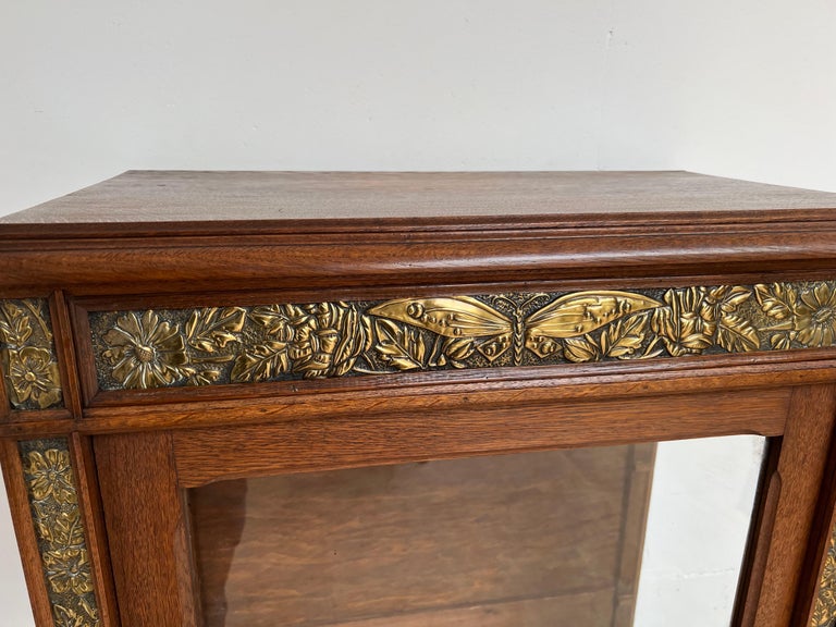 Beautifully handcrafted cabinet with embossed butterflies and flower baskets.

This finest quality early 1900s, single door display cabinet with its original glass panels is a work of art in its own right and it is in good condition. This
