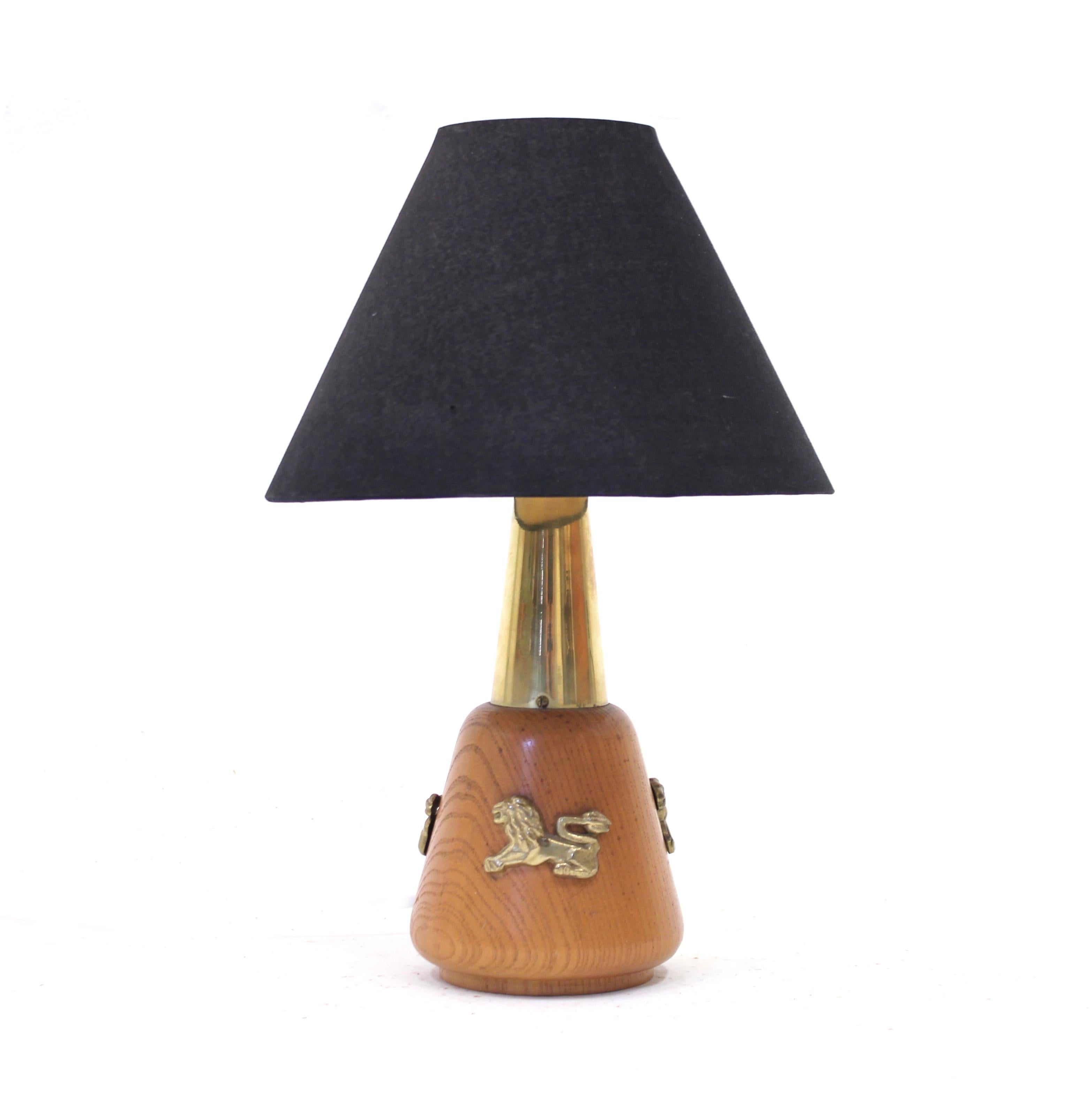 Rare ASEA table lamp in teak and brass with a black shade. Decorated with brass lions on the side of the base. The black shade is vintage but a later addition. Good vintage condition with light ware consistent with age and use.