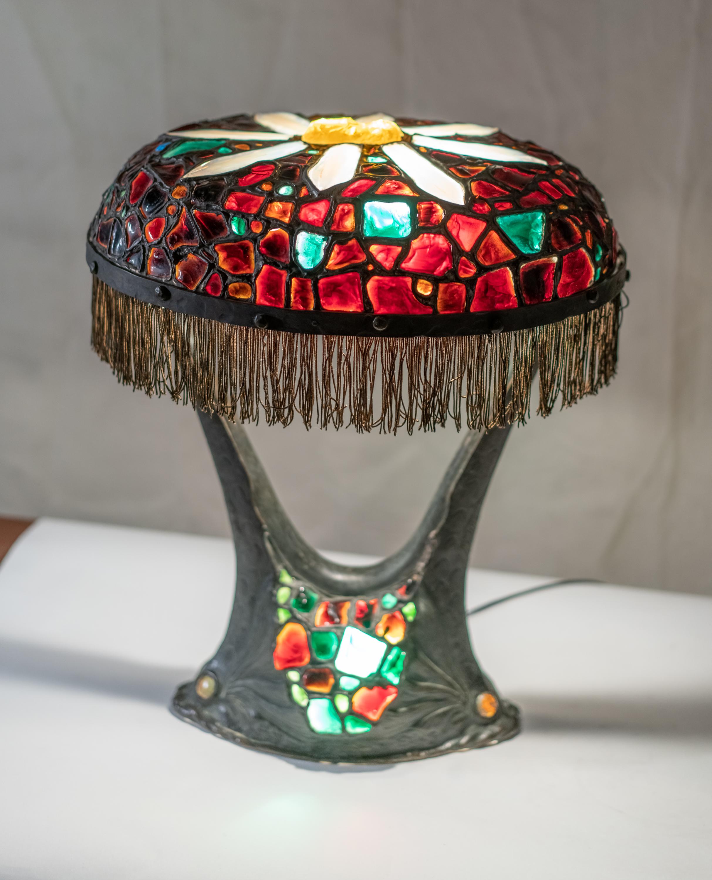 Rare Austrian colorful Art Nouveau bronze and glass chunk jewel table lamp. Attached on bronze sea monster base with eyes en cabochon. The jewels are all handcut and once light up with very vibrant colors.