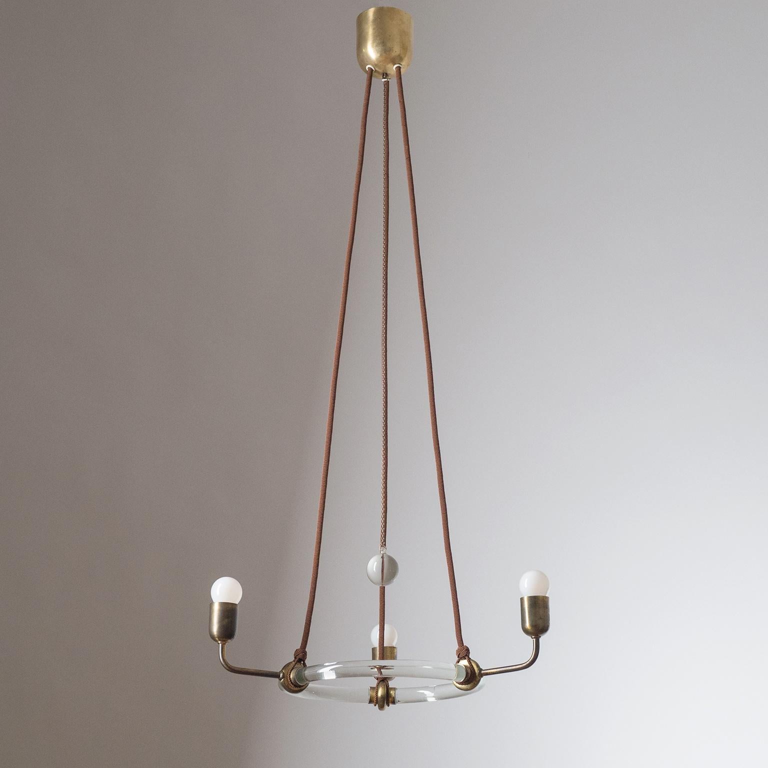 Rare suspension chandelier attributed to Adolf Loos (or his surroundings/pupils). A thick glass ring with three brass arms is suspended by custom cords (re-made after the original). Hanging from the large brass canopy is an original solid glass