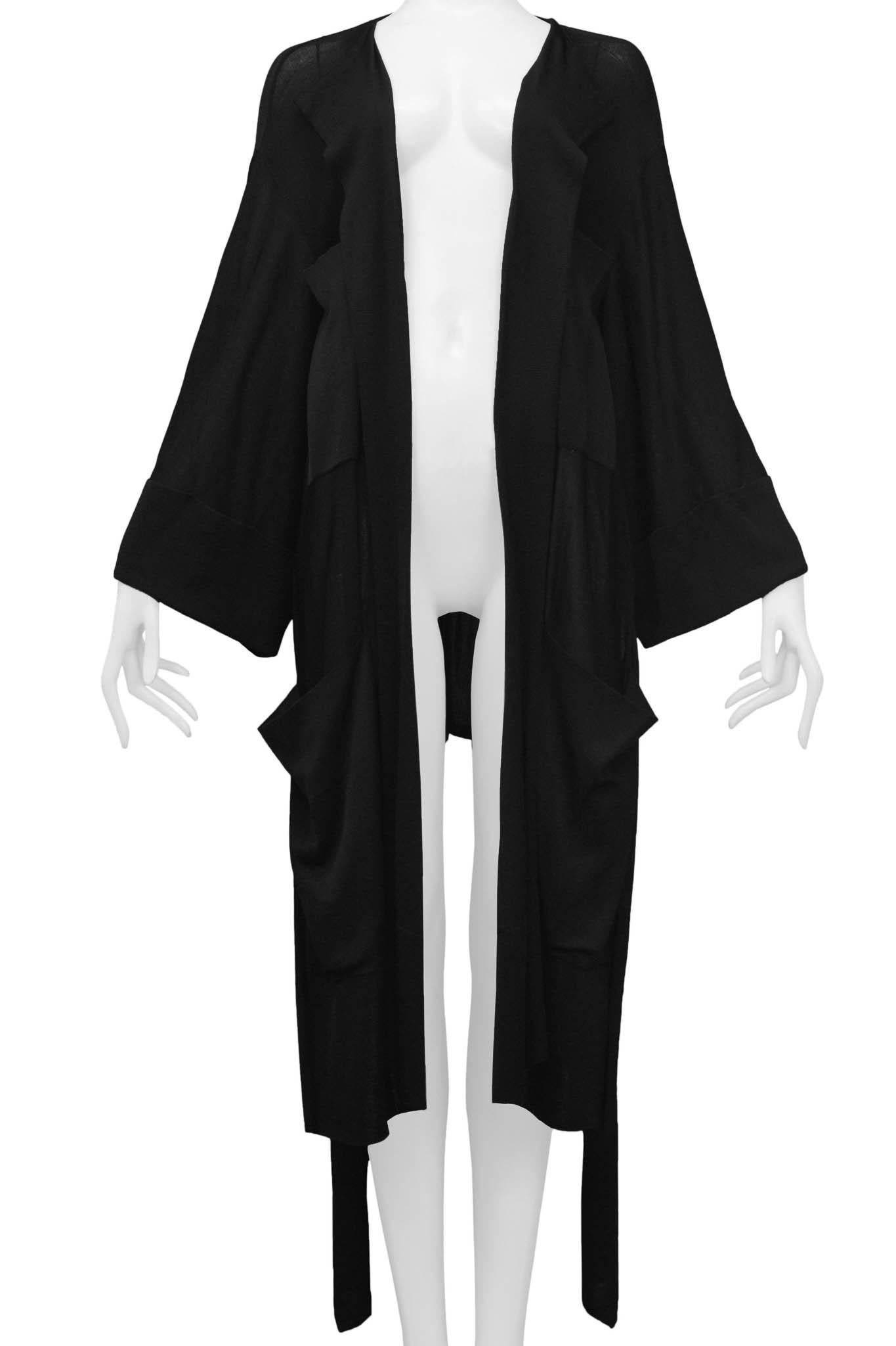 Resurrection Vintage is excited to offer a vintage Azzedine Alaia black knit duster sweater featuring large pockets, side slits, kimono sleeves, and a high low hem. This piece can be worn with a belt (see an editorial from the same collection) or