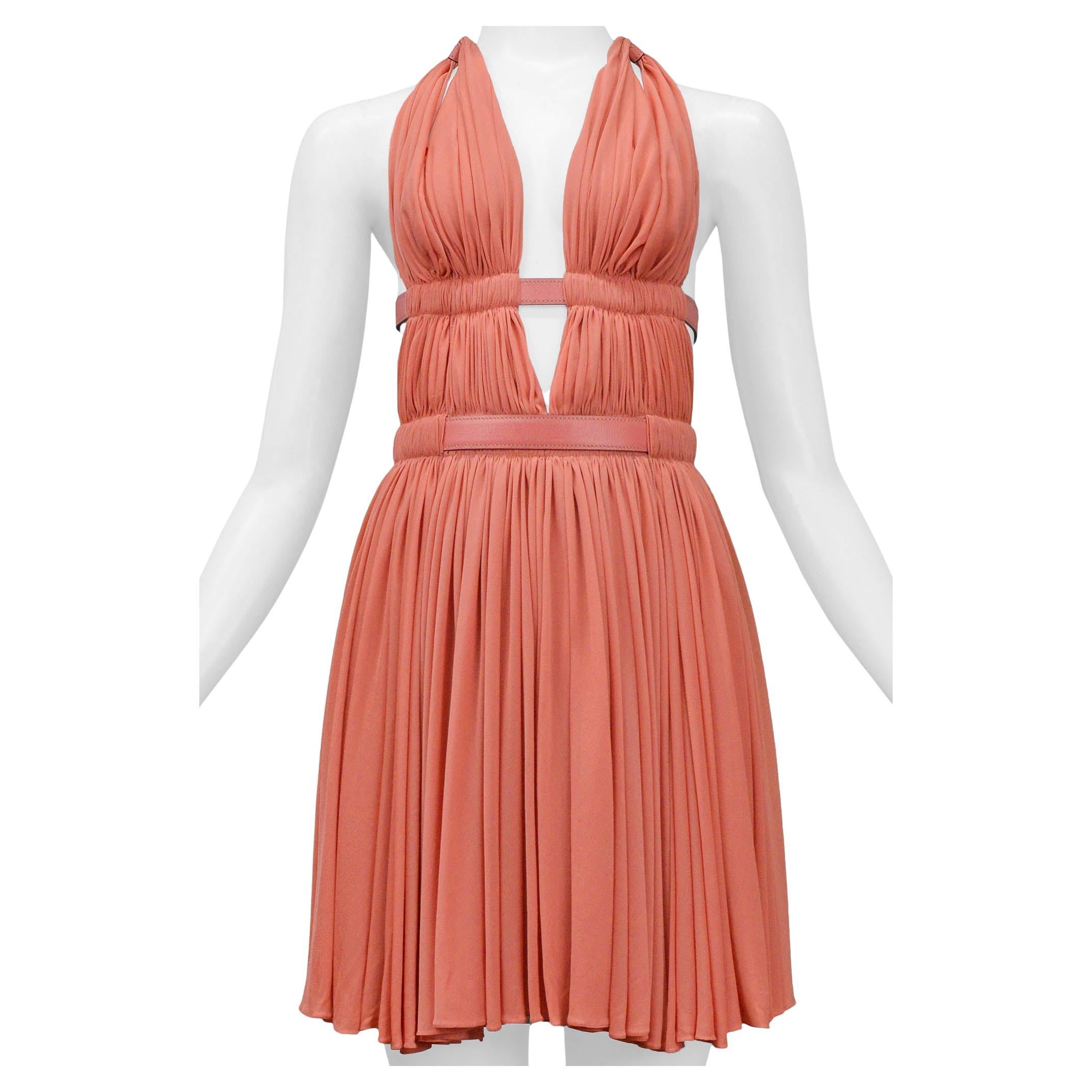 Resurrection Vintage is excited to offer a vintage Azzedine Alaia coral halter dress featuring a deep v, adjustable leather straps with buckles on the neck and back, pleated panels with open slit sides, and peekaboo slits at the back. 

Alaia