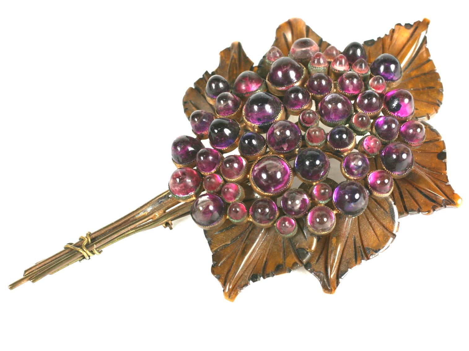 Masive Bakelite and lucite flower unsigned bouquet brooch by B. Blumenthal Co. from the mid 1930s. The brooch consists of olive  green colored hand carved bakelite leaves with amythest glass bezel set bullet cabochons with gilt brass stems wrapped
