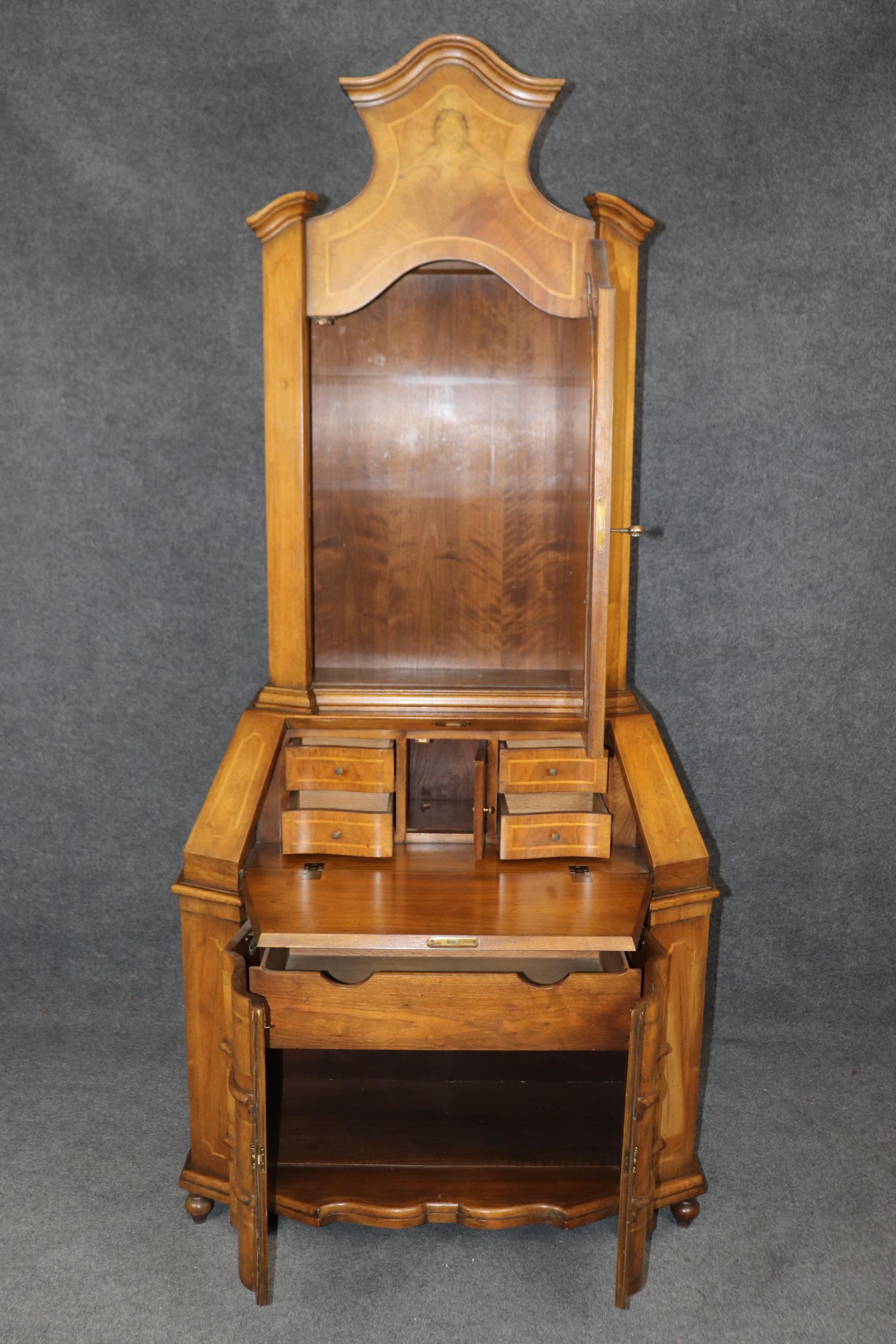 This is a very authentic looking Italian Rococo secretary desk with a bookcase top by Baker furniture company. The piece is made of gorgeous warm walnut and features mirrored doors on top and subtle bronze trim. The piece is in very good condition